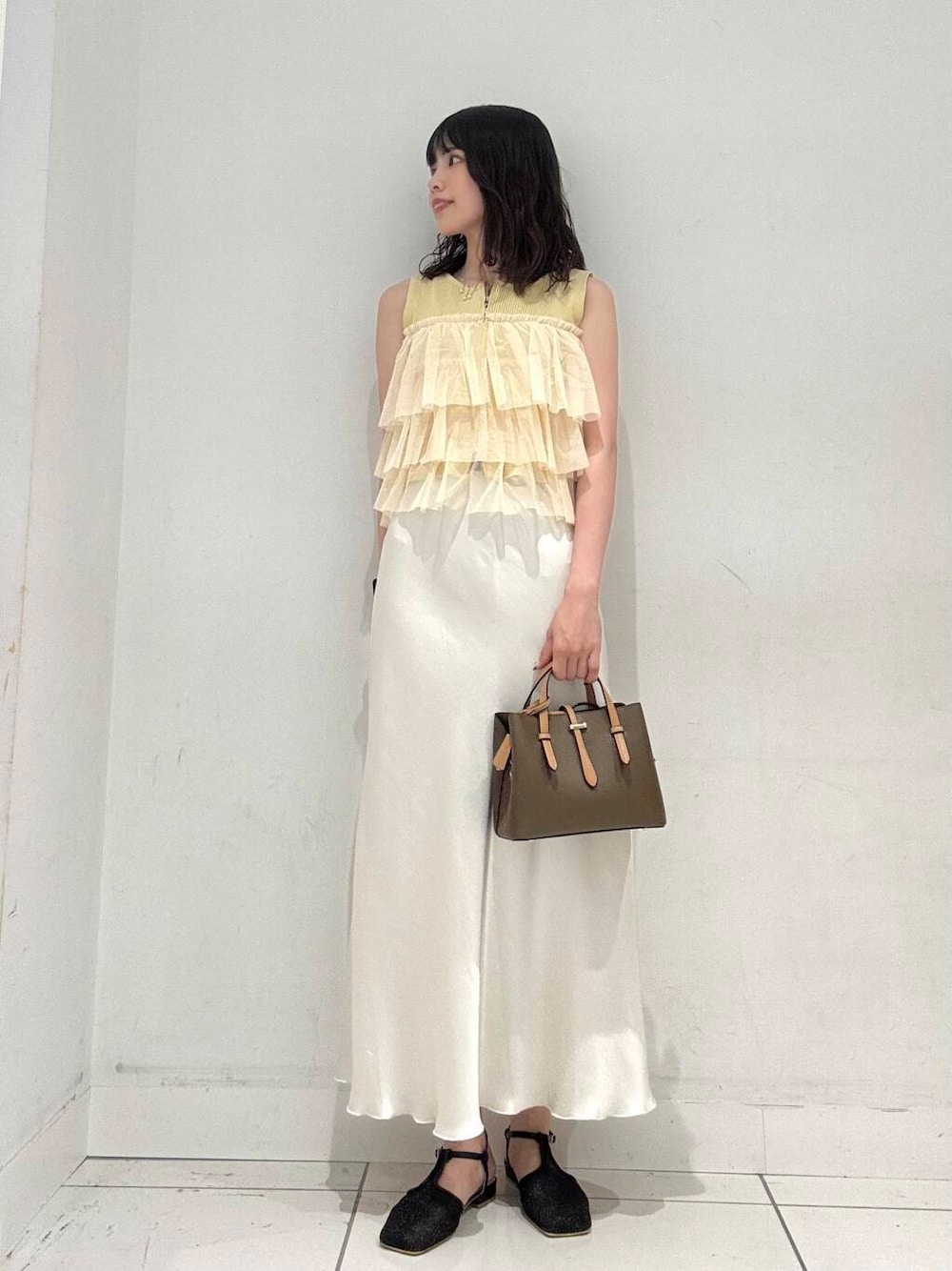 ホワイト系のスカート、ブラウン系のハンドバッグ、ブラック系のパンプスを着用したレディースの夏コーディネートの3枚目の写真