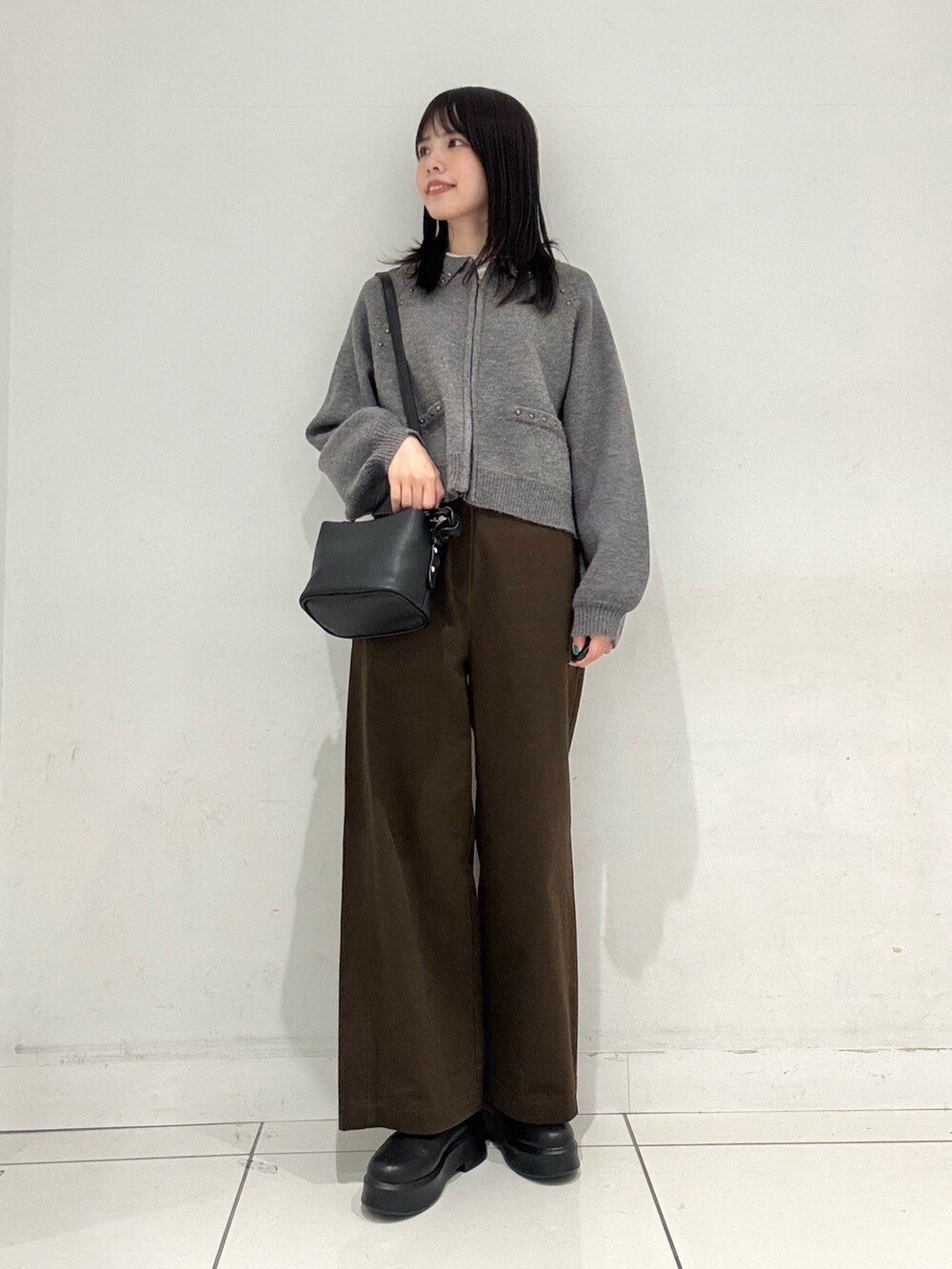 グレー系のカーディガン/ボレロ、ホワイト系のTシャツ/カットソー、ブラック系のショルダーバッグを着用したレディースの冬コーディネートの4枚目の写真