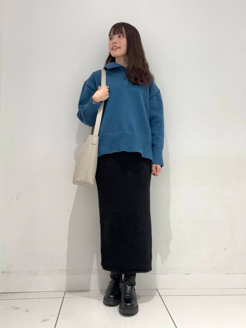 ベージュ系のショルダーバッグ、ブラック系のスカート、ブルー系のニット/セーターを着用したレディースの秋コーディネートの4枚目の写真