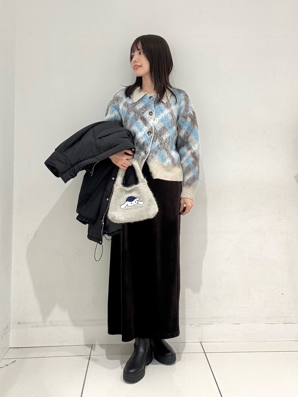 ブルー系のカーディガン/ボレロ、ブラック系のダウンジャケット/コート、ブラウン系のスカートを着用したレディースの冬コーディネートの5枚目の写真