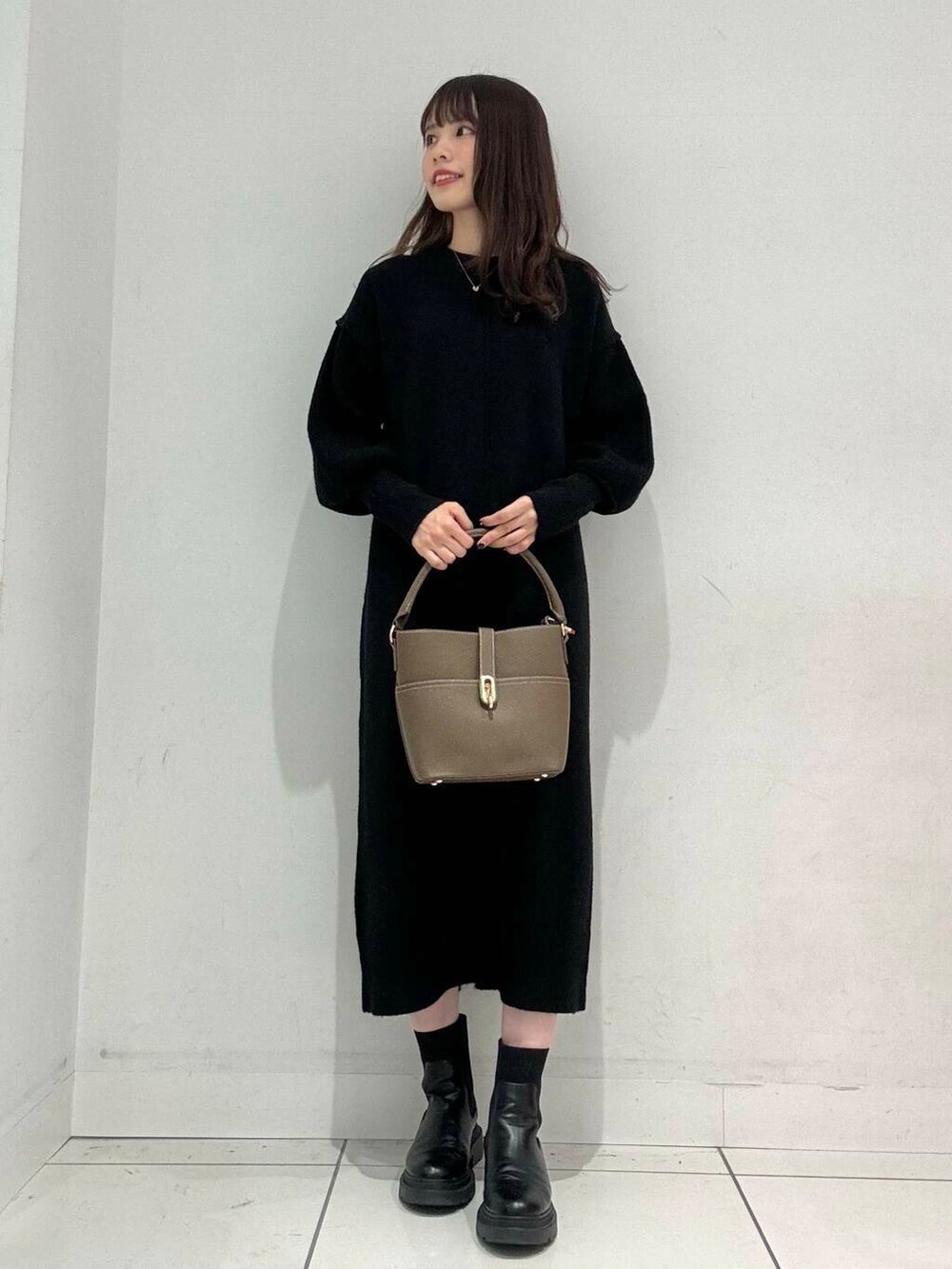 ベージュ系のハンドバッグ、ベージュ系のその他アウター、ブラック系のワンピースを着用したレディースの秋コーディネートの5枚目の写真