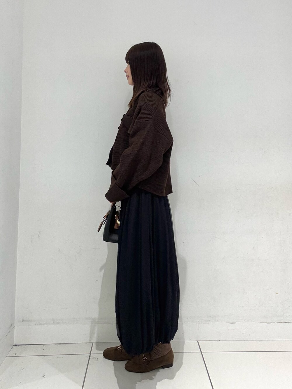 ホワイト系のニット/セーター、ブラウン系のその他アウター、ブラック系のスカートを着用したレディースの秋コーディネートの2枚目の写真