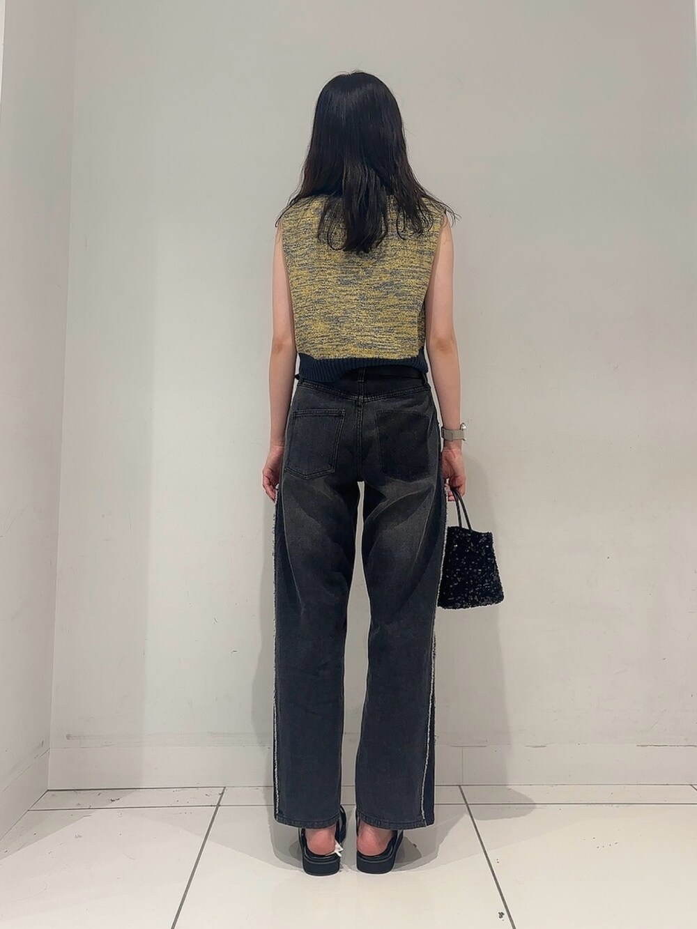 イエロー系のベスト、ブラック系のデニムパンツ、ブラック系のサンダルを着用したレディースの夏コーディネートの3枚目の写真