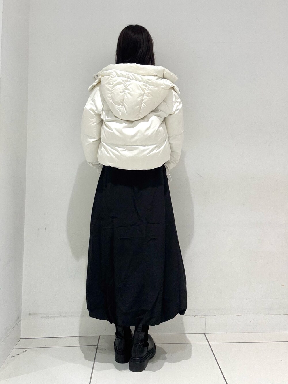 ブラック系のスカート、ブラウン系のニット/セーター、ホワイト系のダウンジャケット/コートを着用したレディースの冬コーディネートの4枚目の写真