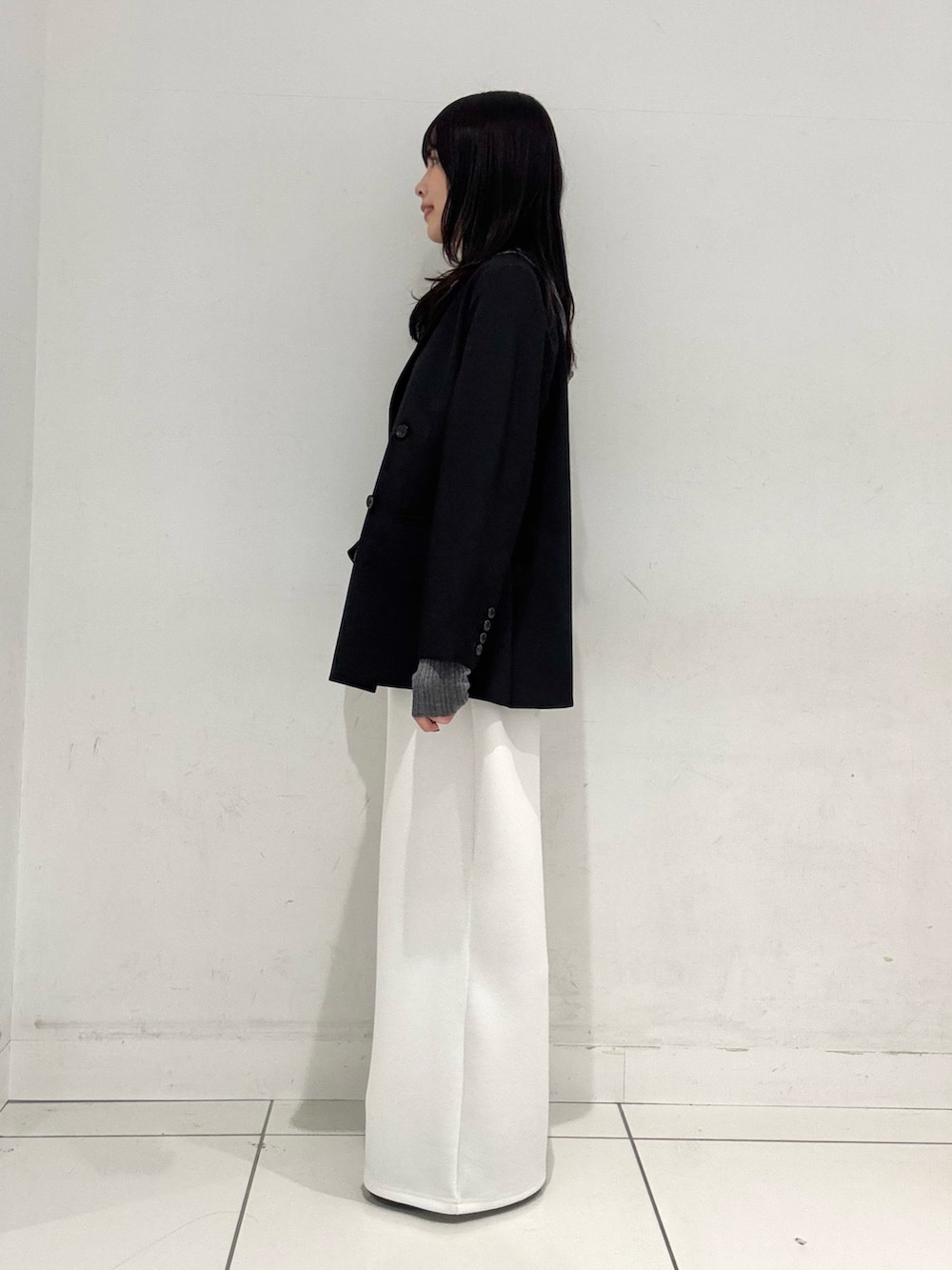 ブラック系のテーラードジャケット、グレー系のニット/セーター、ホワイト系のその他パンツを着用したレディースの春コーディネートの2枚目の写真