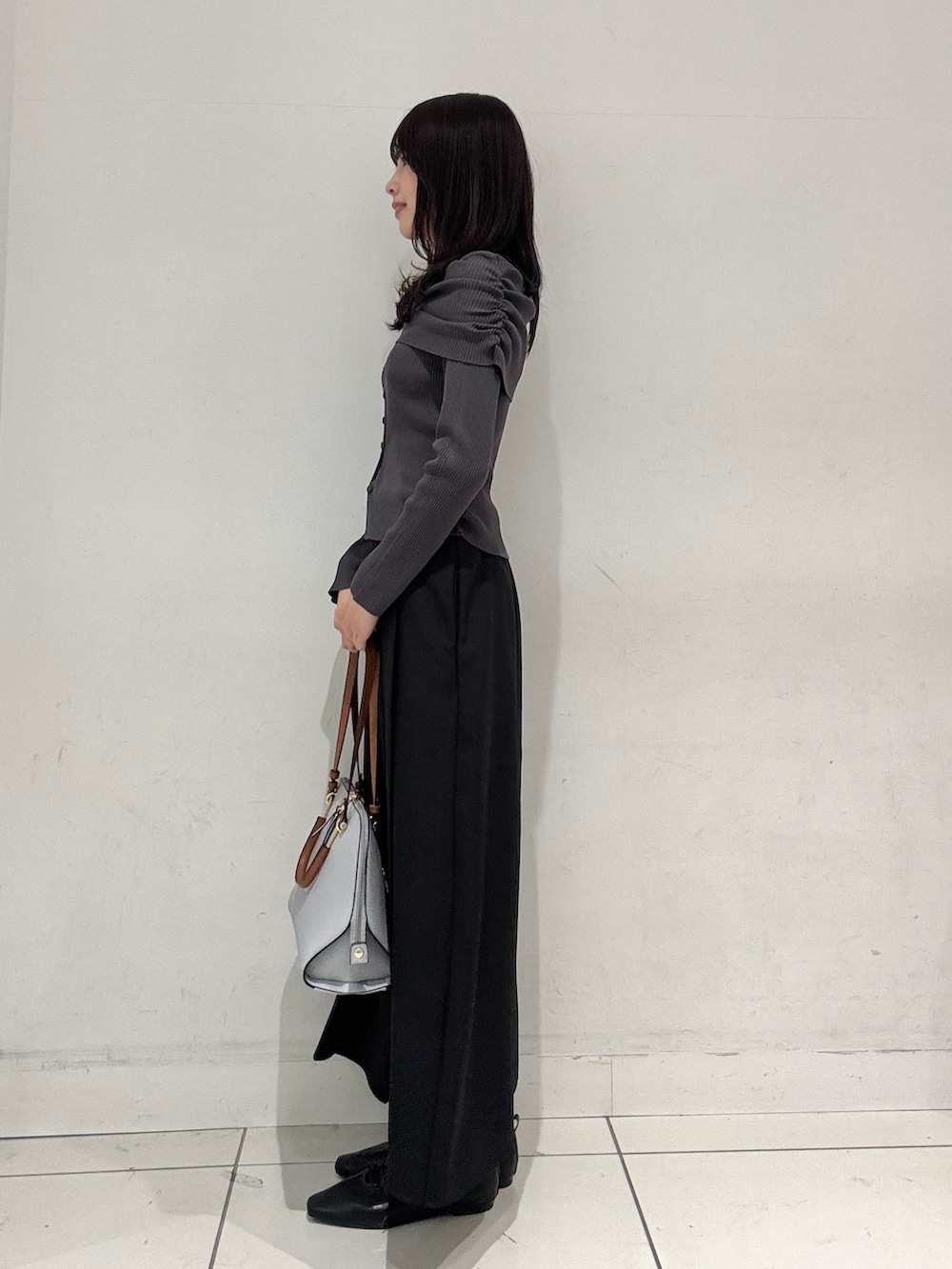 グレー系のニット/セーター、ブラック系のスカート、ブラック系のその他シューズを着用したレディースの冬コーディネートの2枚目の写真