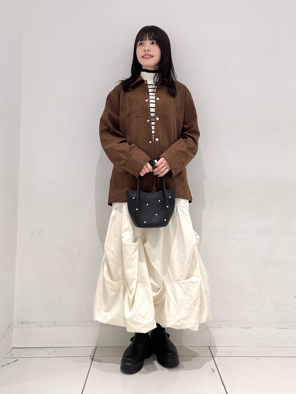 ホワイト系のスカート、ブラウン系のその他アウター、ホワイト系のニット/セーターを着用したレディースの冬コーディネートの4枚目の写真