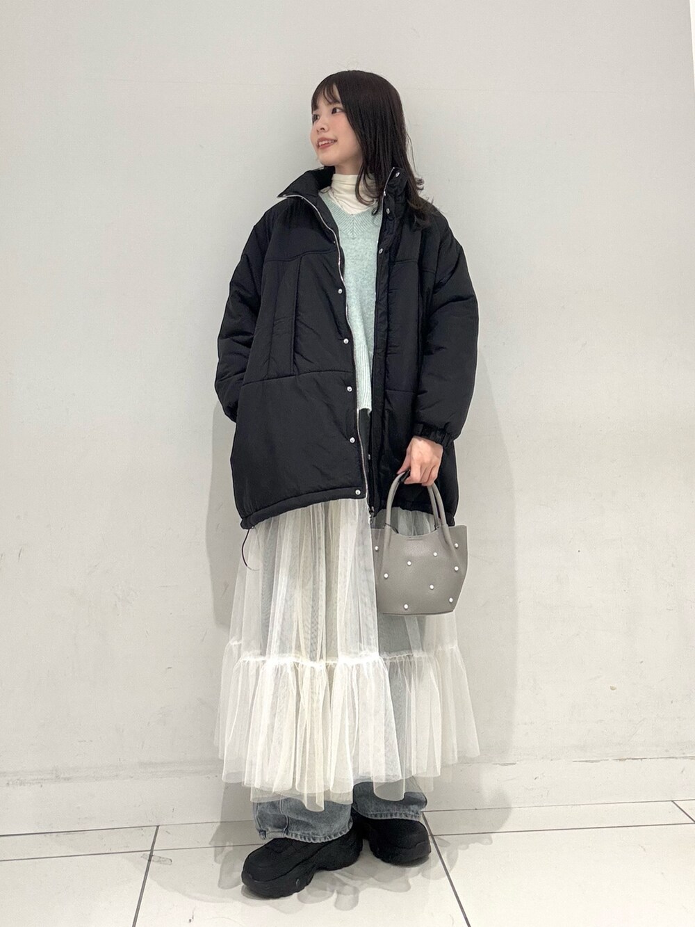 ホワイト系のTシャツ/カットソー、グリーン系のニット/セーター、ホワイト系のスカートを着用したレディースの冬コーディネートの3枚目の写真