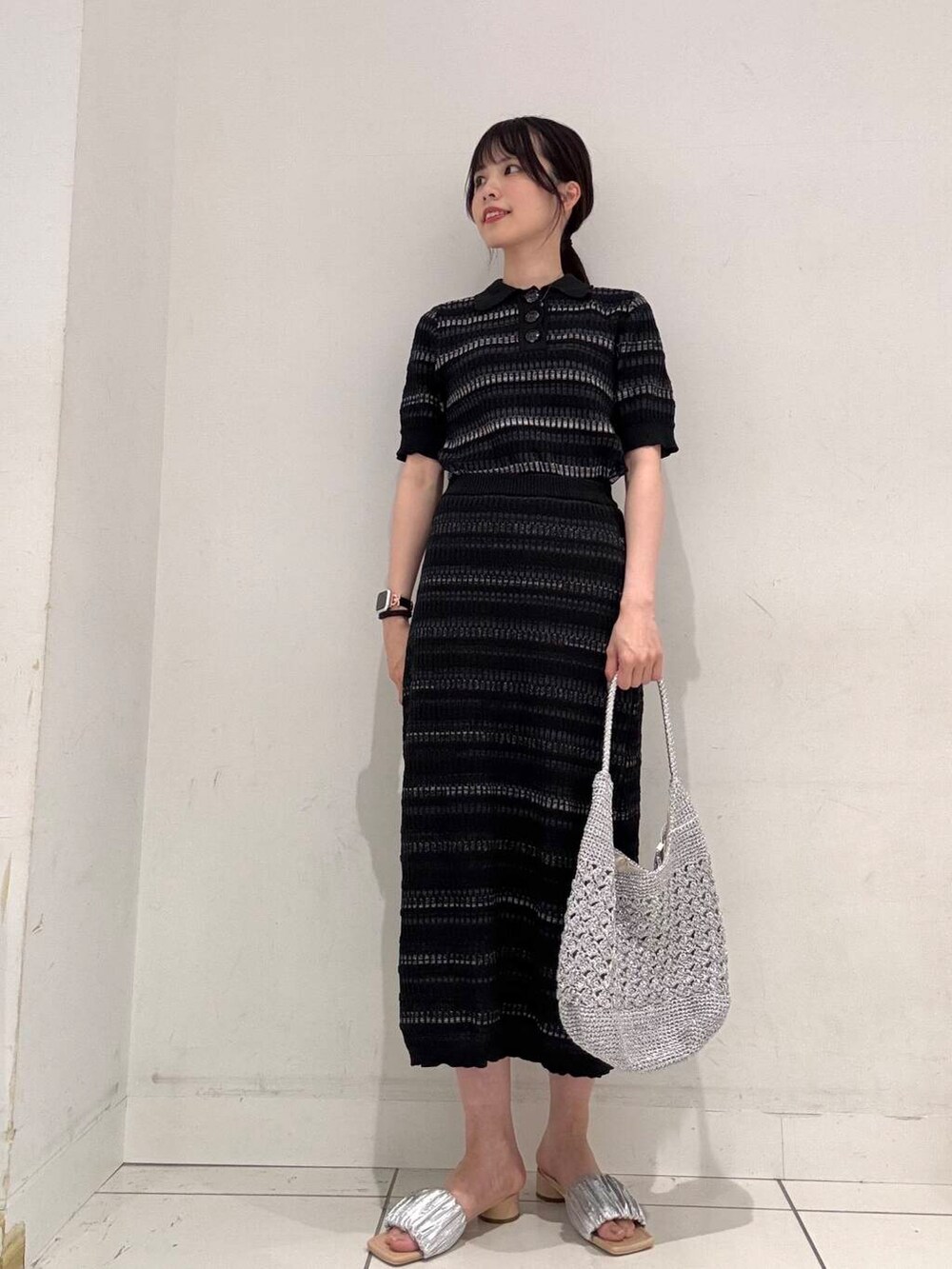 シルバー系のハンドバッグ、シルバー系のサンダル、ブラック系のニット/セーターを着用したレディースの夏コーディネートの4枚目の写真
