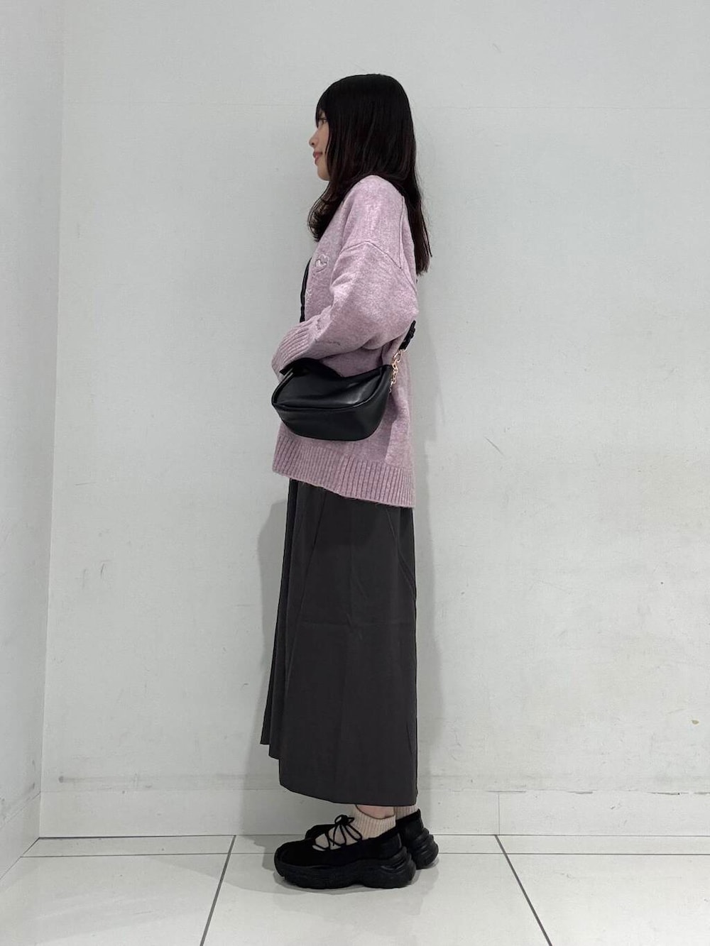 ブラック系のショルダーバッグ、グレー系のワンピース、ブラック系のスニーカーを着用したレディースの冬コーディネートの2枚目の写真