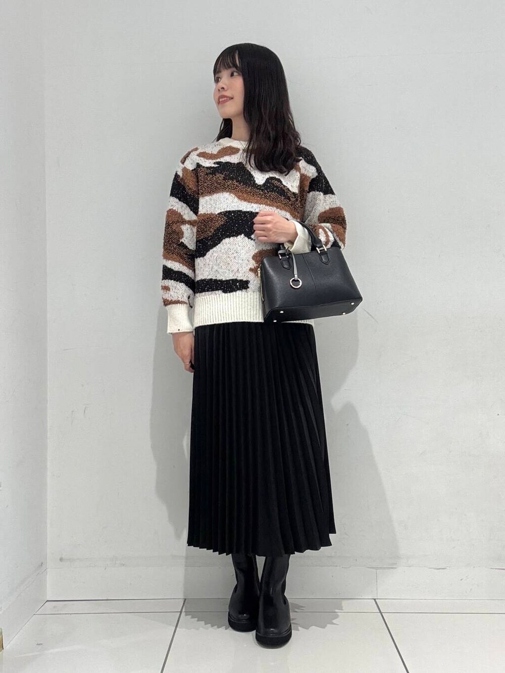ホワイト系のニット/セーター、ブラック系のブーツ、ブラック系のハンドバッグを着用したレディースの冬コーディネートの4枚目の写真