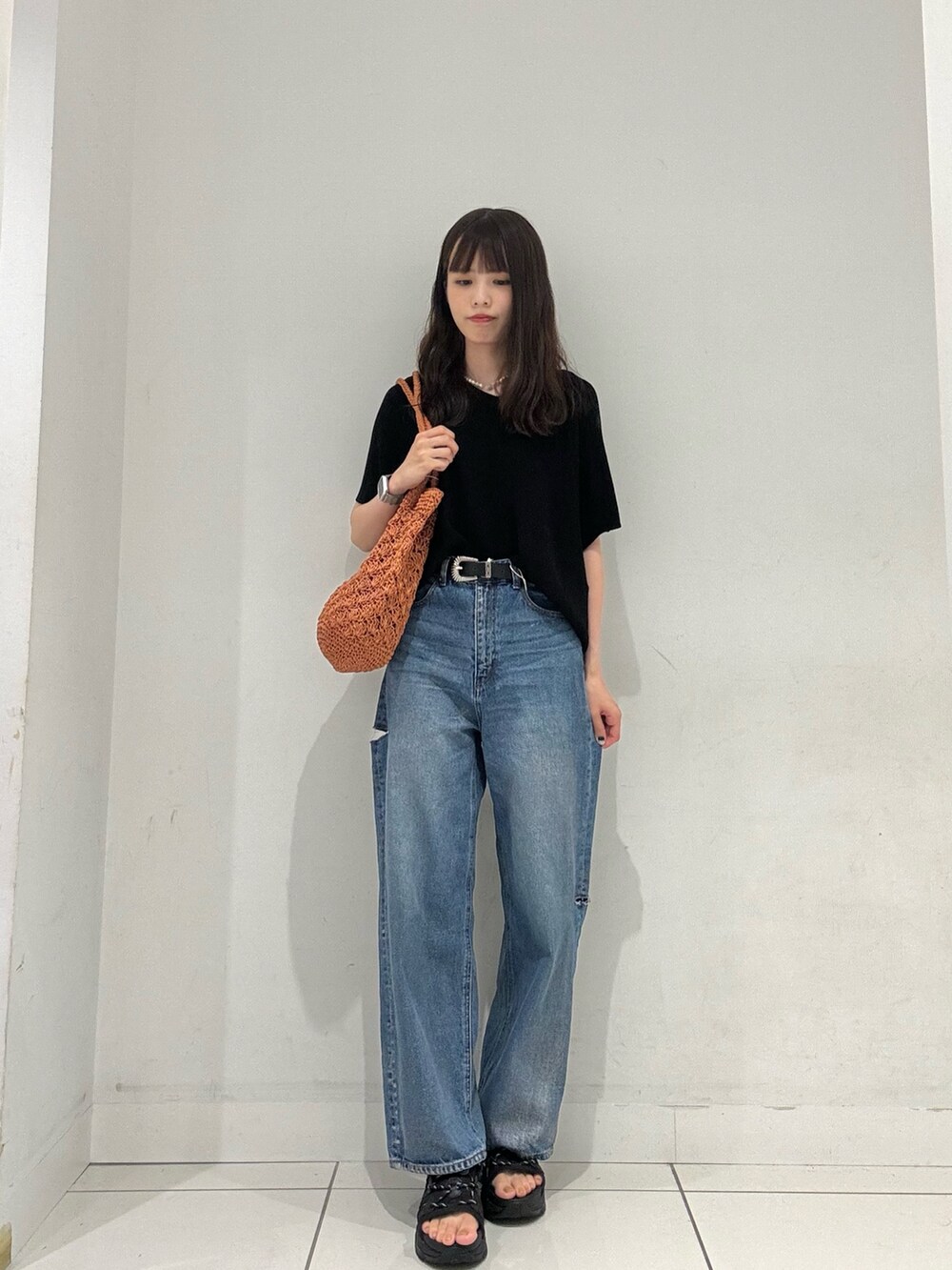 ブラック系のニット/セーター、ブルー系のその他パンツ、オレンジ系のトートバッグを着用したレディースの夏コーディネートの4枚目の写真