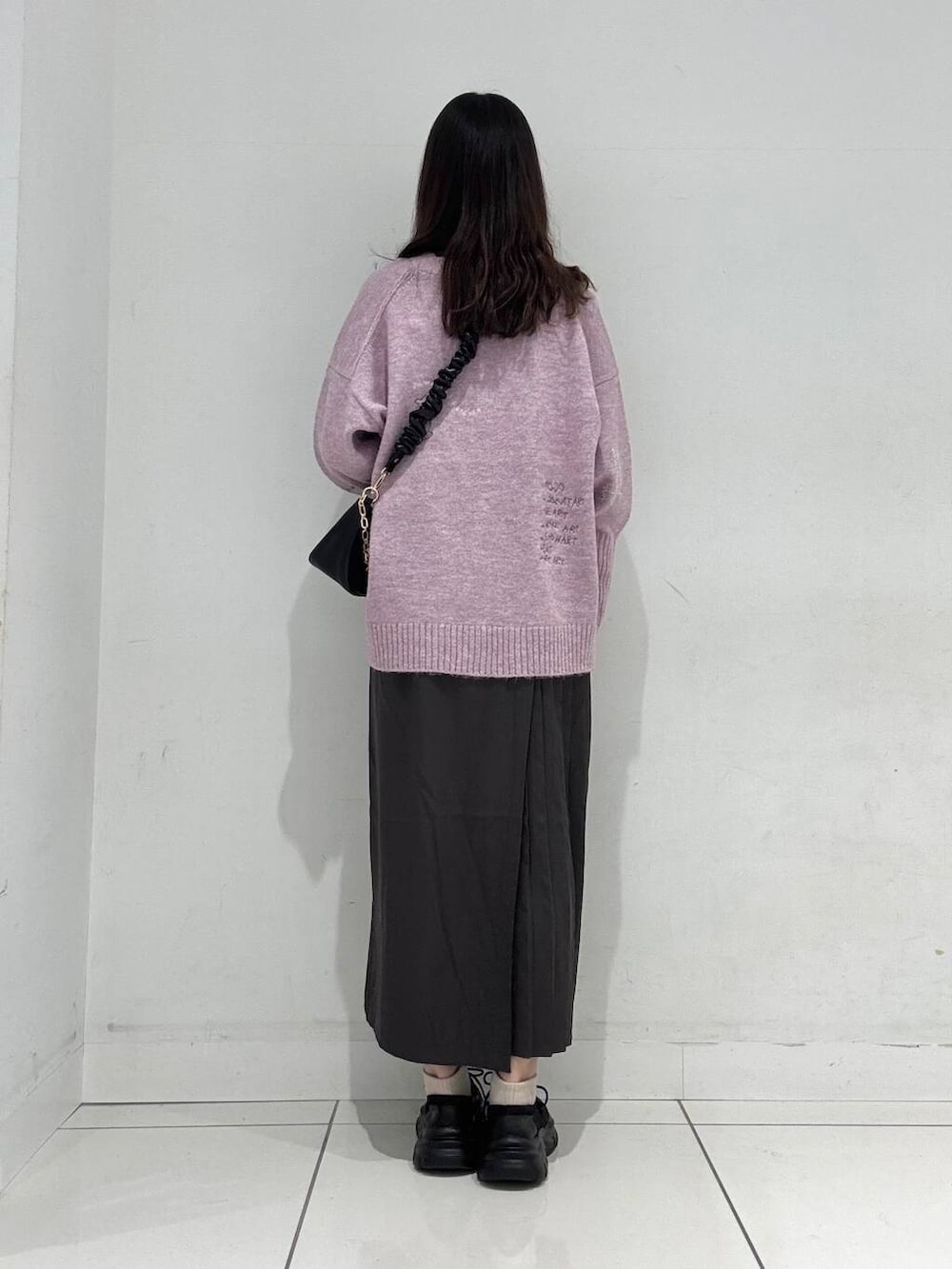 ブラック系のショルダーバッグ、グレー系のワンピース、ブラック系のスニーカーを着用したレディースの冬コーディネートの3枚目の写真