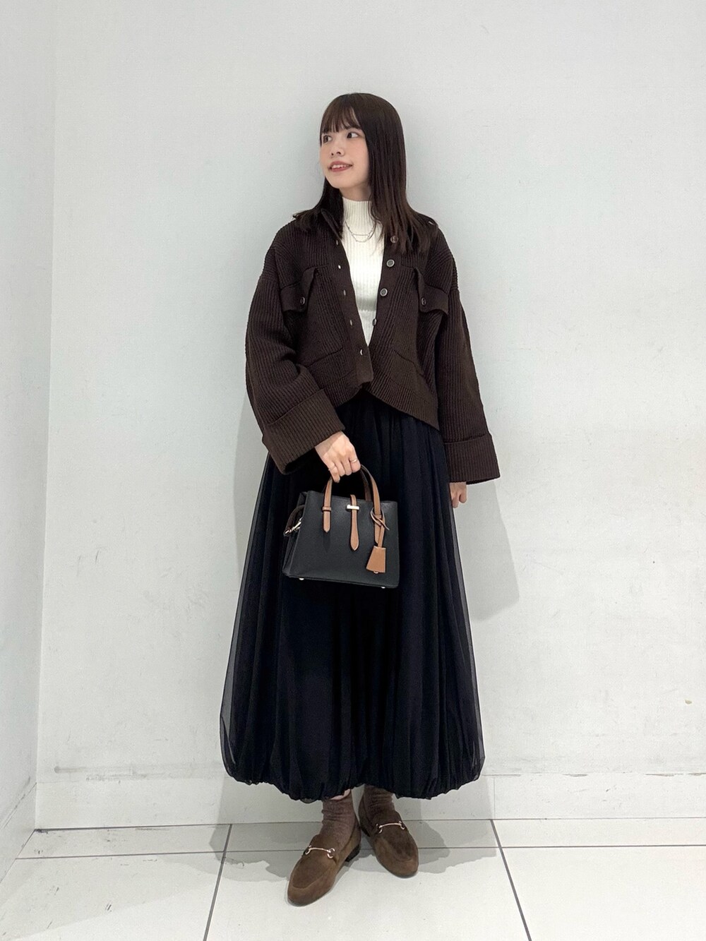 ホワイト系のニット/セーター、ブラウン系のその他アウター、ブラック系のスカートを着用したレディースの秋コーディネートの4枚目の写真