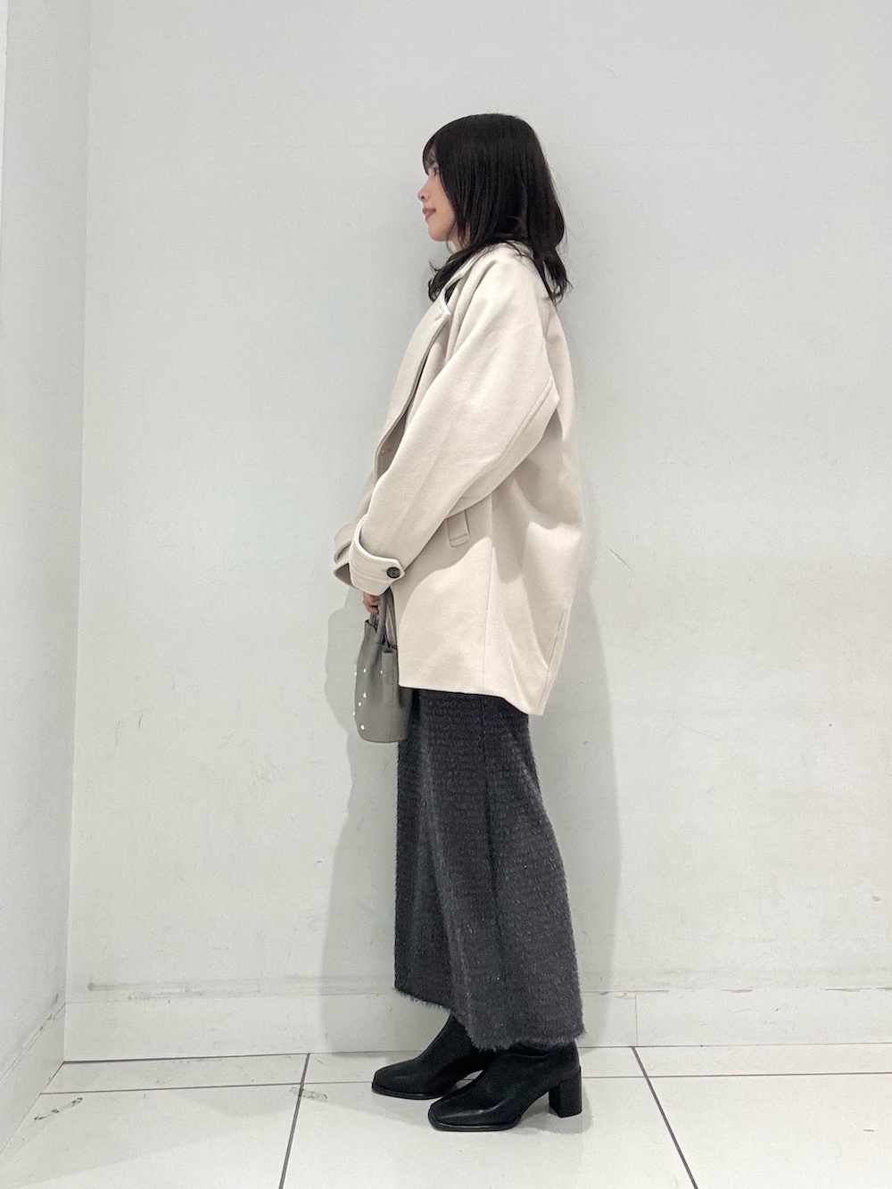 ブルー系のニット/セーター、ベージュ系のその他アウター、グレー系のスカートを着用したレディースの冬コーディネートの2枚目の写真