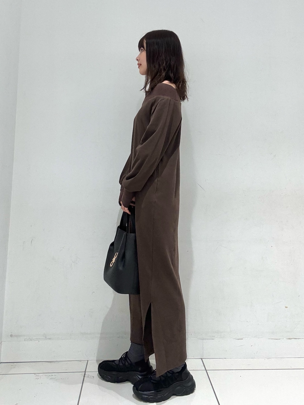 ブラウン系のワンピース、ブラック系のスニーカー、ブラック系のトートバッグを着用したレディースの秋コーディネートの2枚目の写真