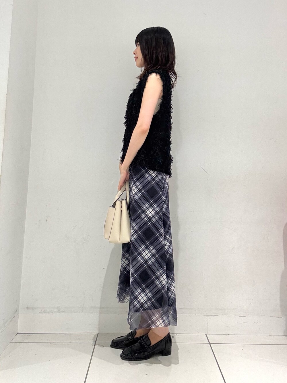 ブラック系のベスト、ホワイト系のキャミソール、ブルー系のスカートを着用したレディースの夏コーディネートの2枚目の写真