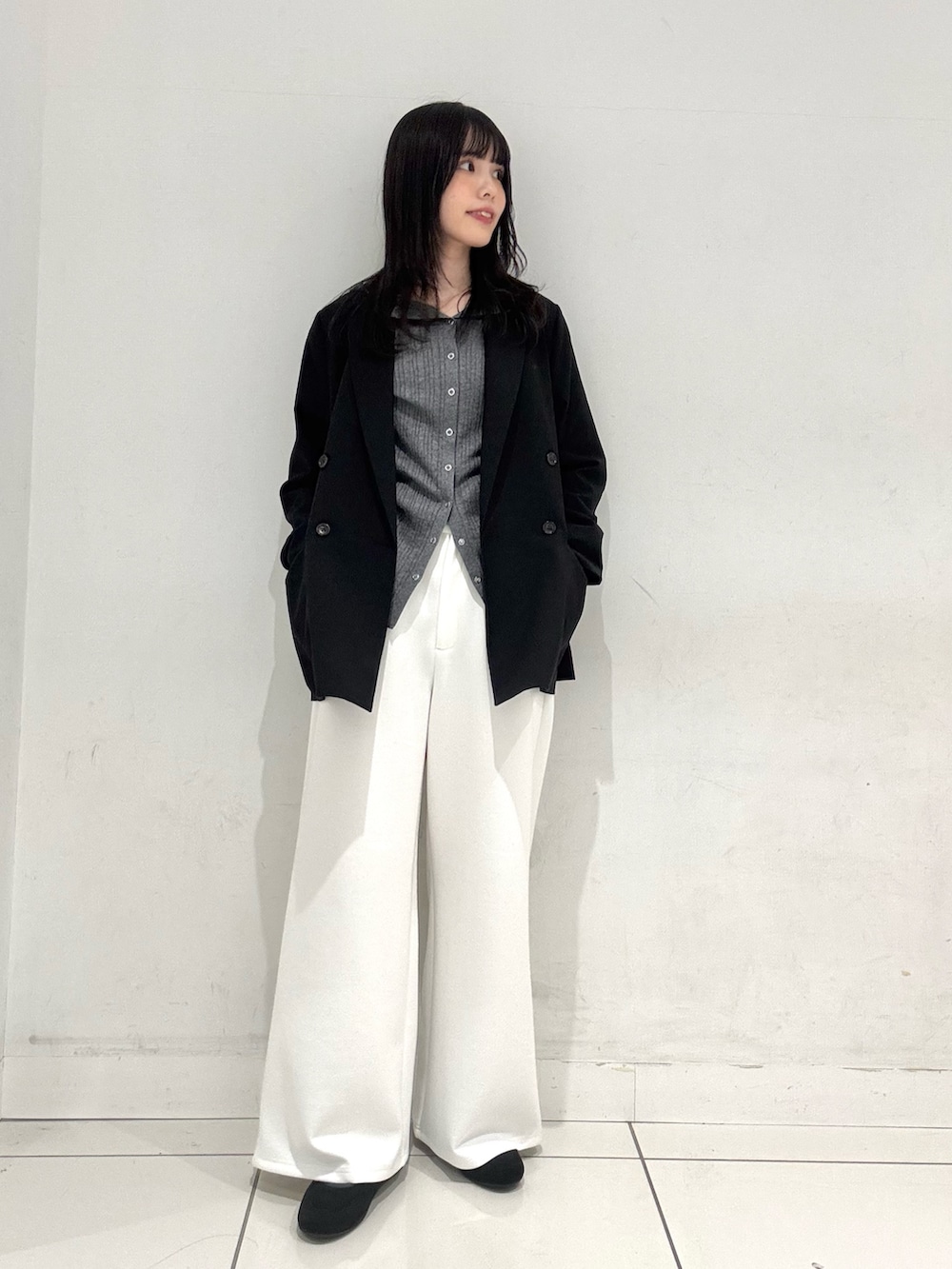 ブラック系のテーラードジャケット、グレー系のニット/セーター、ホワイト系のその他パンツを着用したレディースの春コーディネートの4枚目の写真