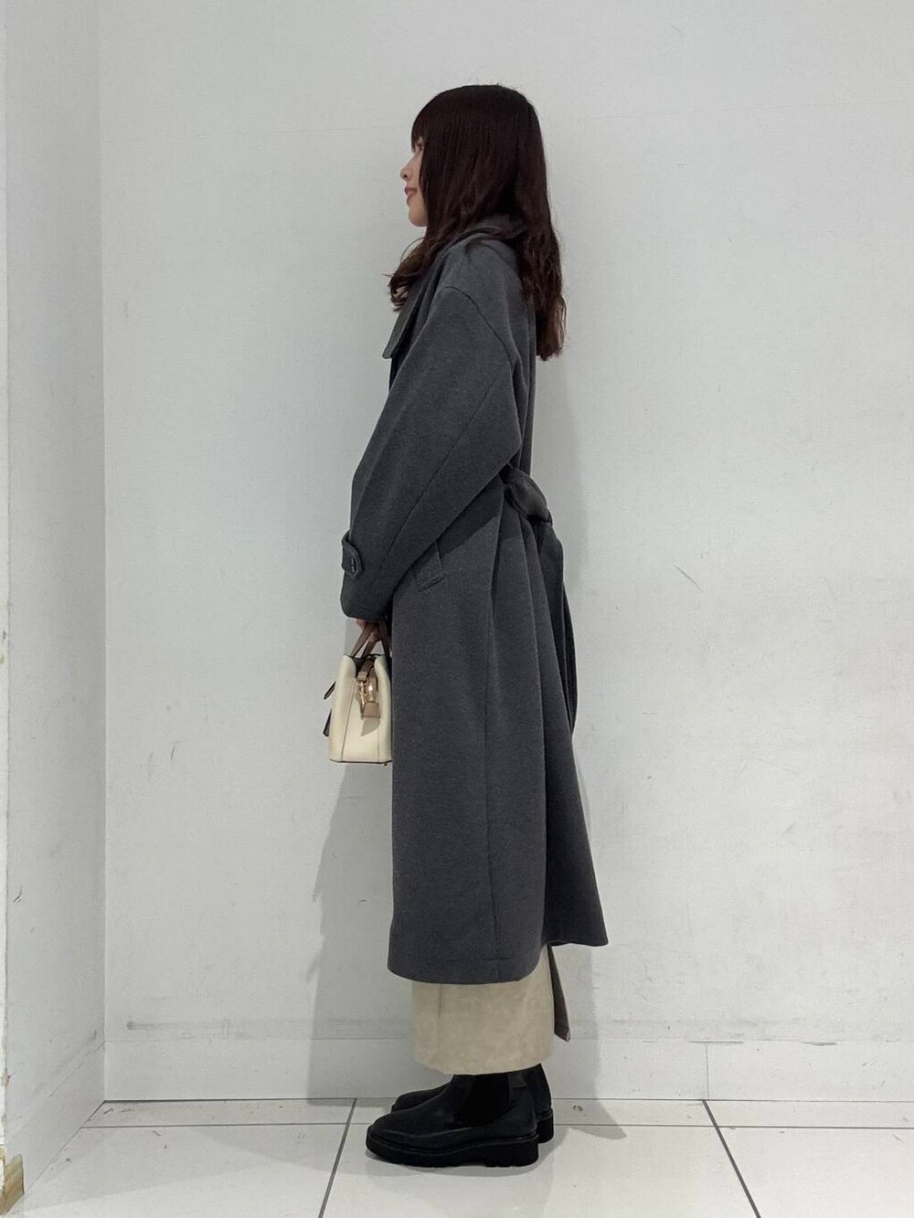 ホワイト系のハンドバッグ、レッド系のニット/セーター、ホワイト系のスカートを着用したレディースの冬コーディネートの3枚目の写真