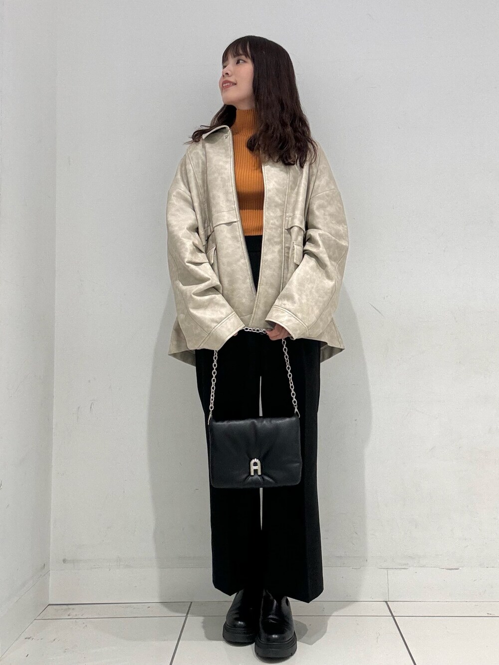 オレンジ系のニット/セーター、ホワイト系のその他アウター、ブラック系のその他パンツを着用したレディースの秋コーディネートの4枚目の写真