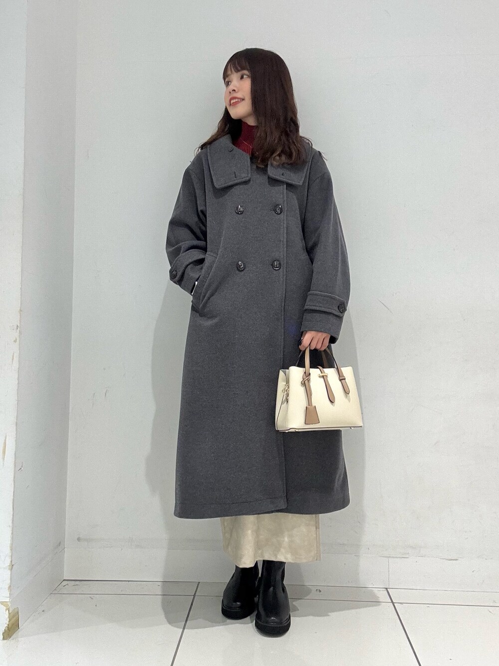 レッド系のニット/セーター、グレー系のその他アウター、ホワイト系のスカートを着用したレディースの冬コーディネートの2枚目の写真