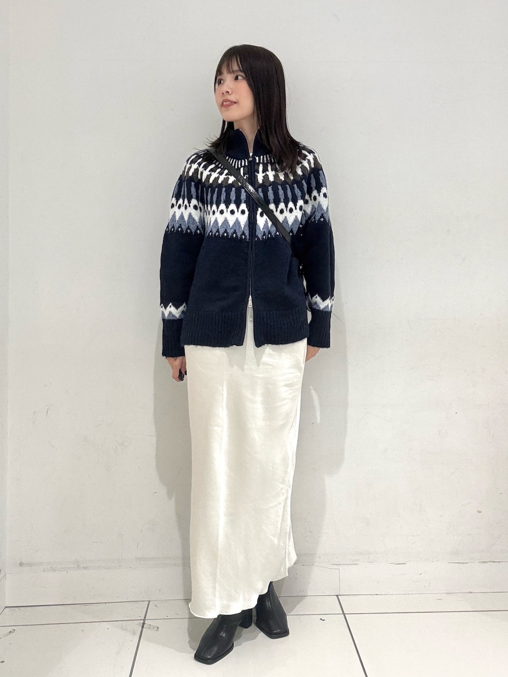 ブルー系のニット/セーター、ホワイト系のスカート、ブラック系のショルダーバッグを着用したレディースの秋コーディネートの4枚目の写真