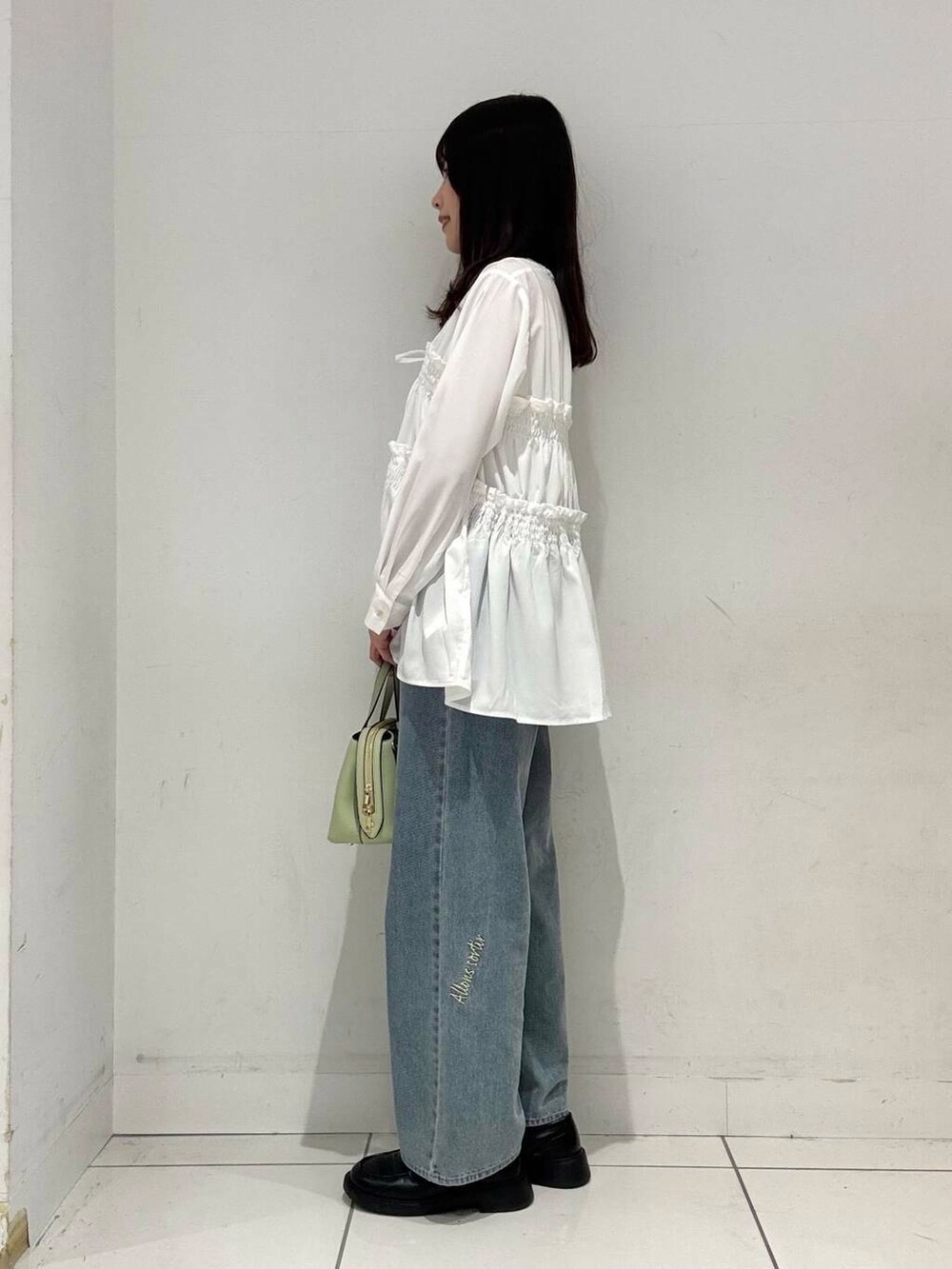 グリーン系のトートバッグ、ブルー系のデニムパンツ、ホワイト系のシャツ/ブラウスを着用したレディースの春コーディネートの2枚目の写真