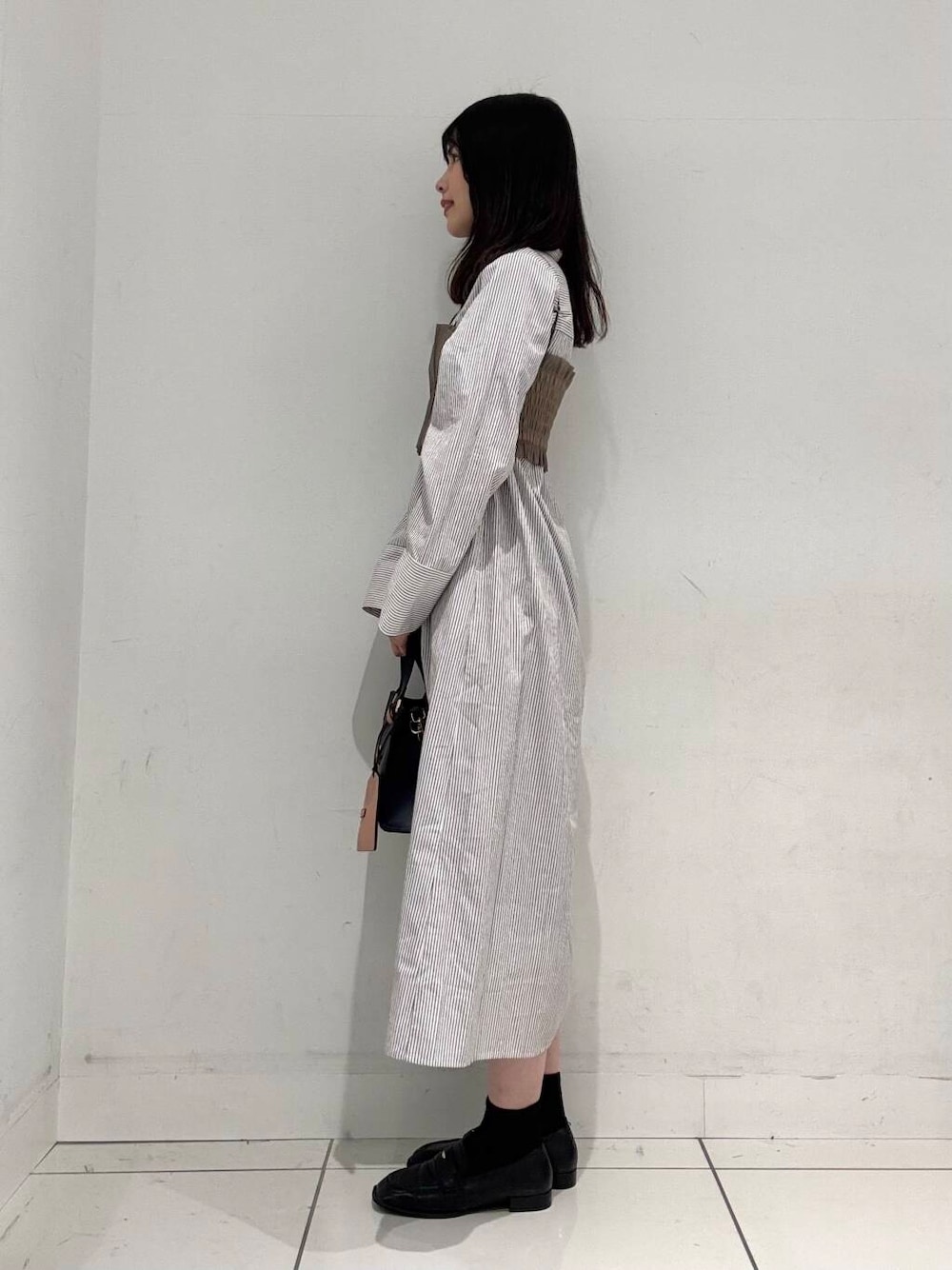 ブルー系のハンドバッグ、ブラック系のローファー、ベージュ系のワンピースを着用したレディースの春コーディネートの2枚目の写真