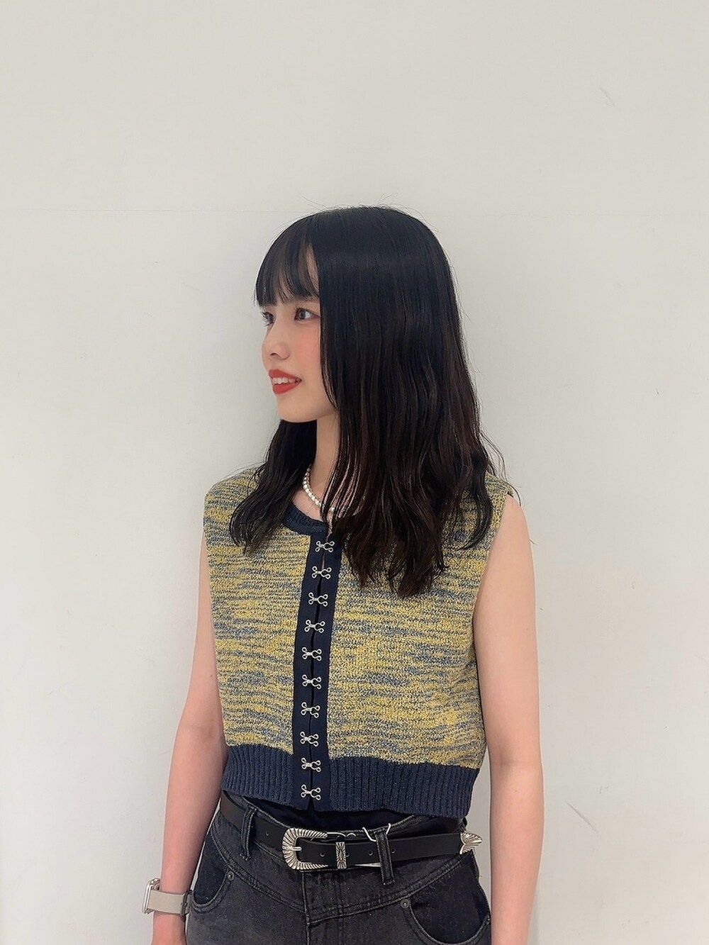 イエロー系のベスト、ブラック系のデニムパンツ、ブラック系のサンダルを着用したレディースの夏コーディネートの4枚目の写真