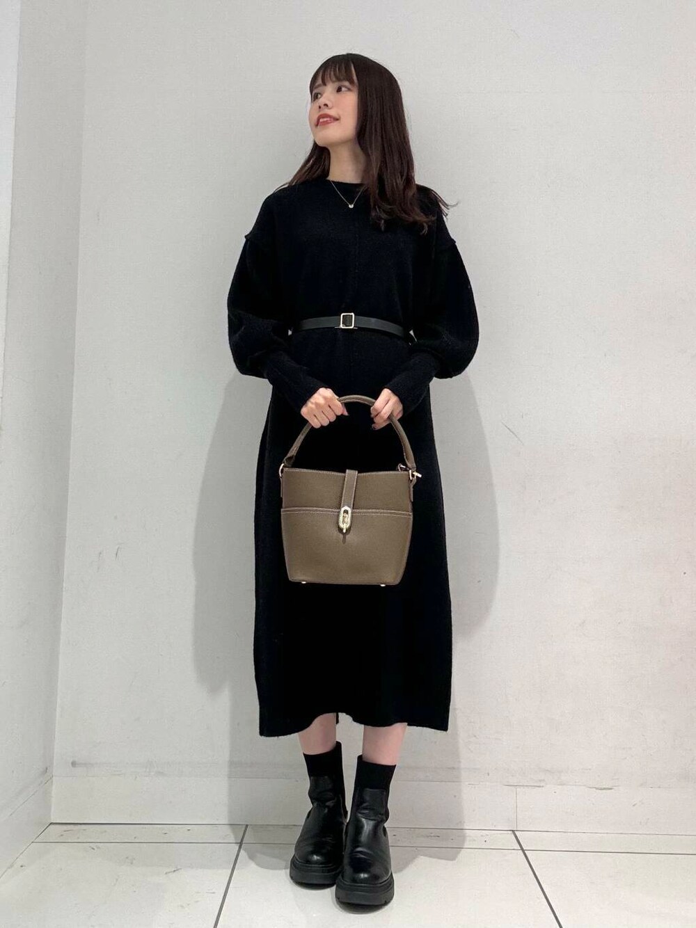 ベージュ系のハンドバッグ、ベージュ系のその他アウター、ブラック系のワンピースを着用したレディースの秋コーディネートの4枚目の写真