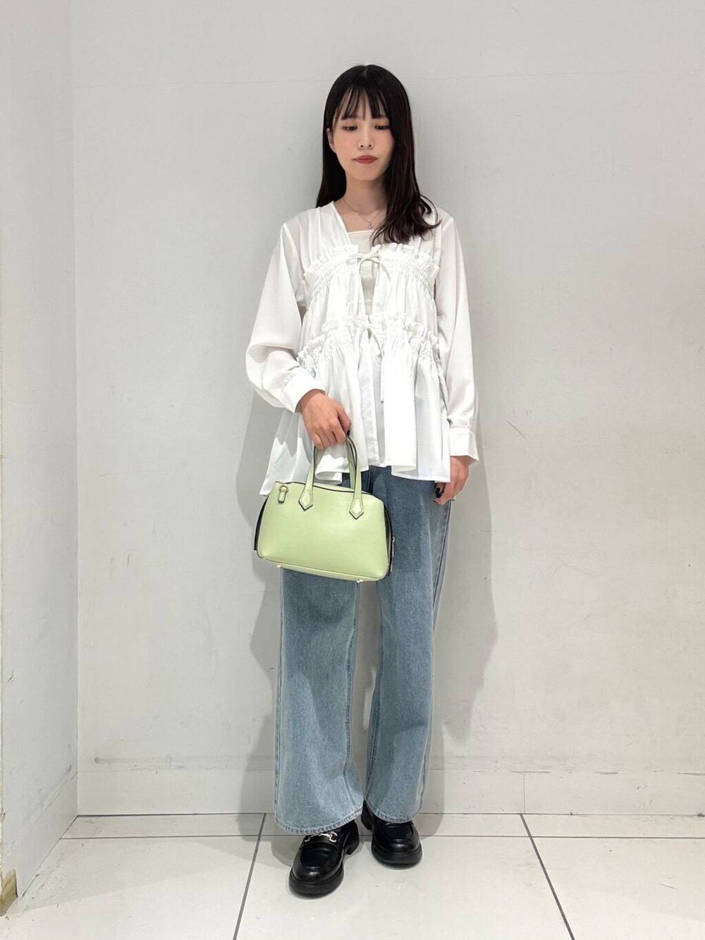 グリーン系のトートバッグ、ブルー系のデニムパンツ、ホワイト系のシャツ/ブラウスを着用したレディースの春コーディネートの5枚目の写真