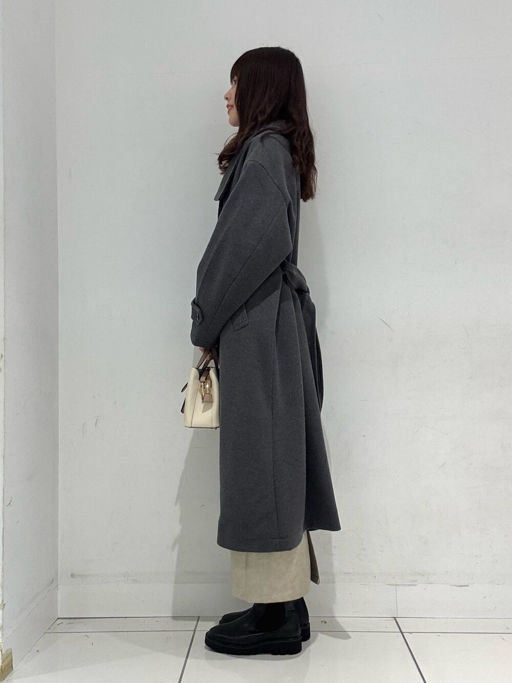 レッド系のニット/セーター、グレー系のその他アウター、ホワイト系のスカートを着用したレディースの冬コーディネートの3枚目の写真