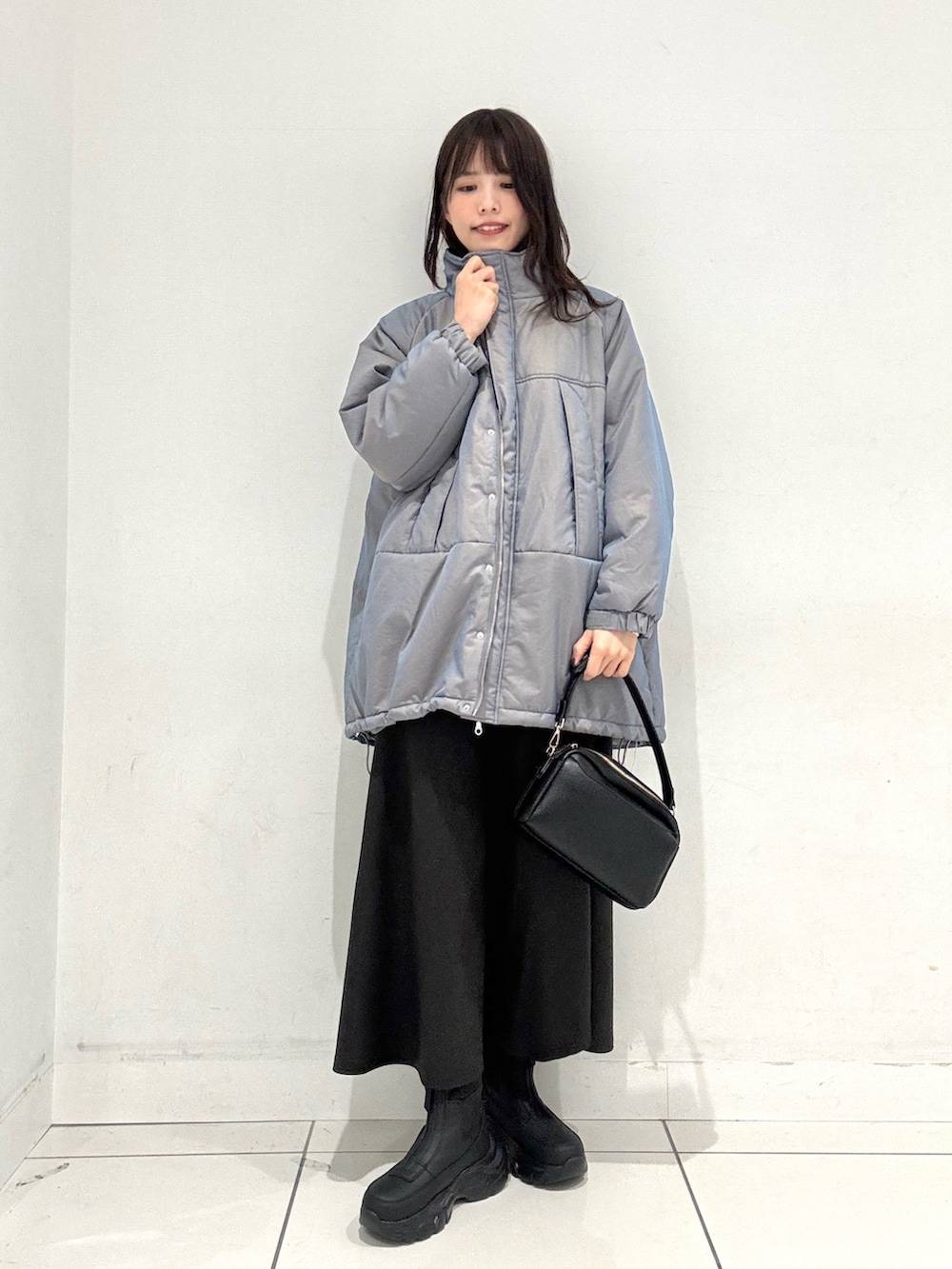 グレー系のスカート、ホワイト系のニット/セーター、グリーン系のダウンジャケット/コートを着用したレディースの秋コーディネートの3枚目の写真