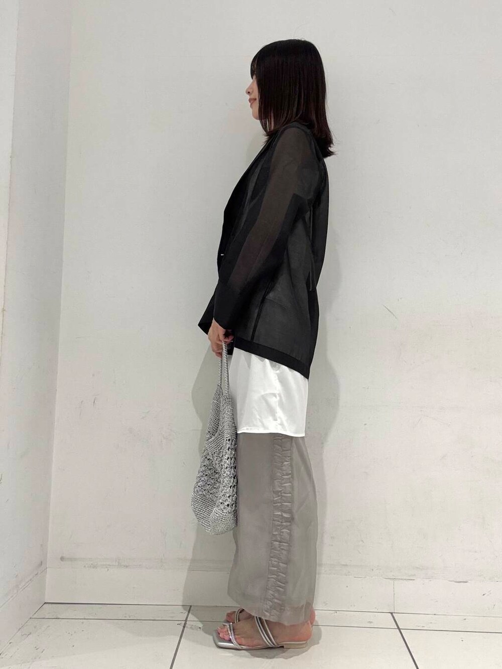 シルバー系のハンドバッグ、ホワイト系のタンクトップ、シルバー系のサンダルを着用したレディースの夏コーディネートの2枚目の写真