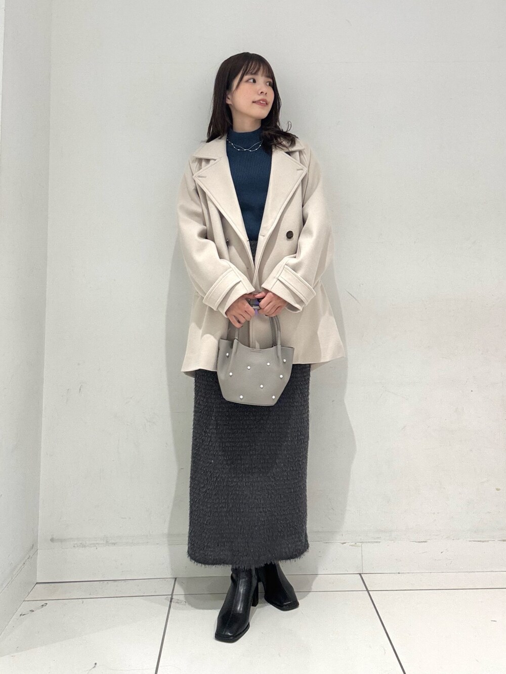 ブルー系のニット/セーター、ベージュ系のその他アウター、グレー系のスカートを着用したレディースの冬コーディネートの4枚目の写真