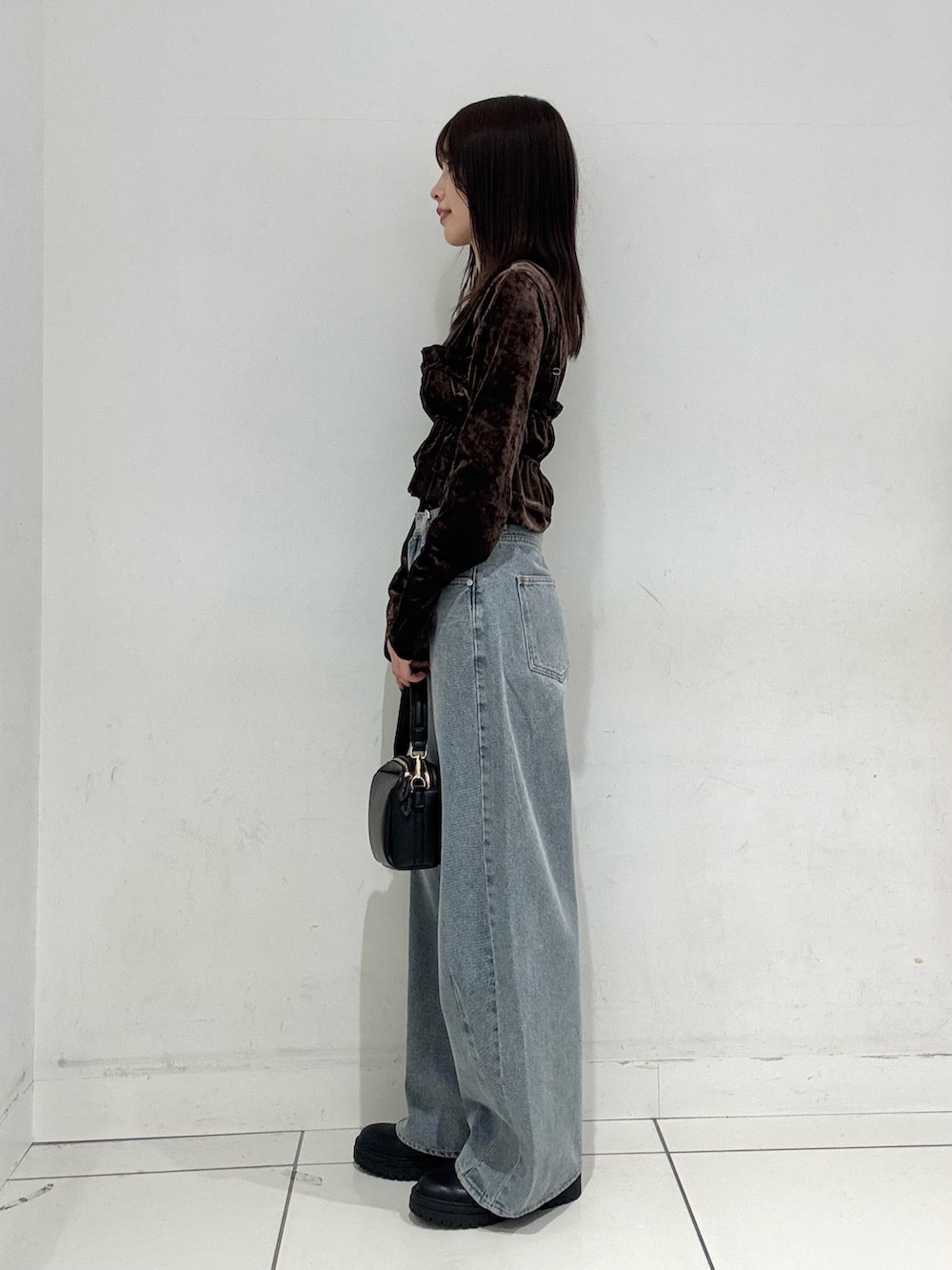 ブラウン系のTシャツ/カットソー、ブルー系のデニムパンツ、ブラック系のショルダーバッグを着用したレディースの冬コーディネートの2枚目の写真