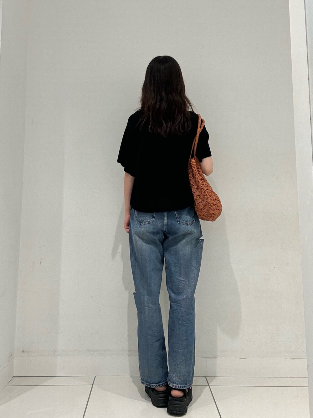 ブラック系のニット/セーター、ブルー系のその他パンツ、オレンジ系のトートバッグを着用したレディースの夏コーディネートの3枚目の写真