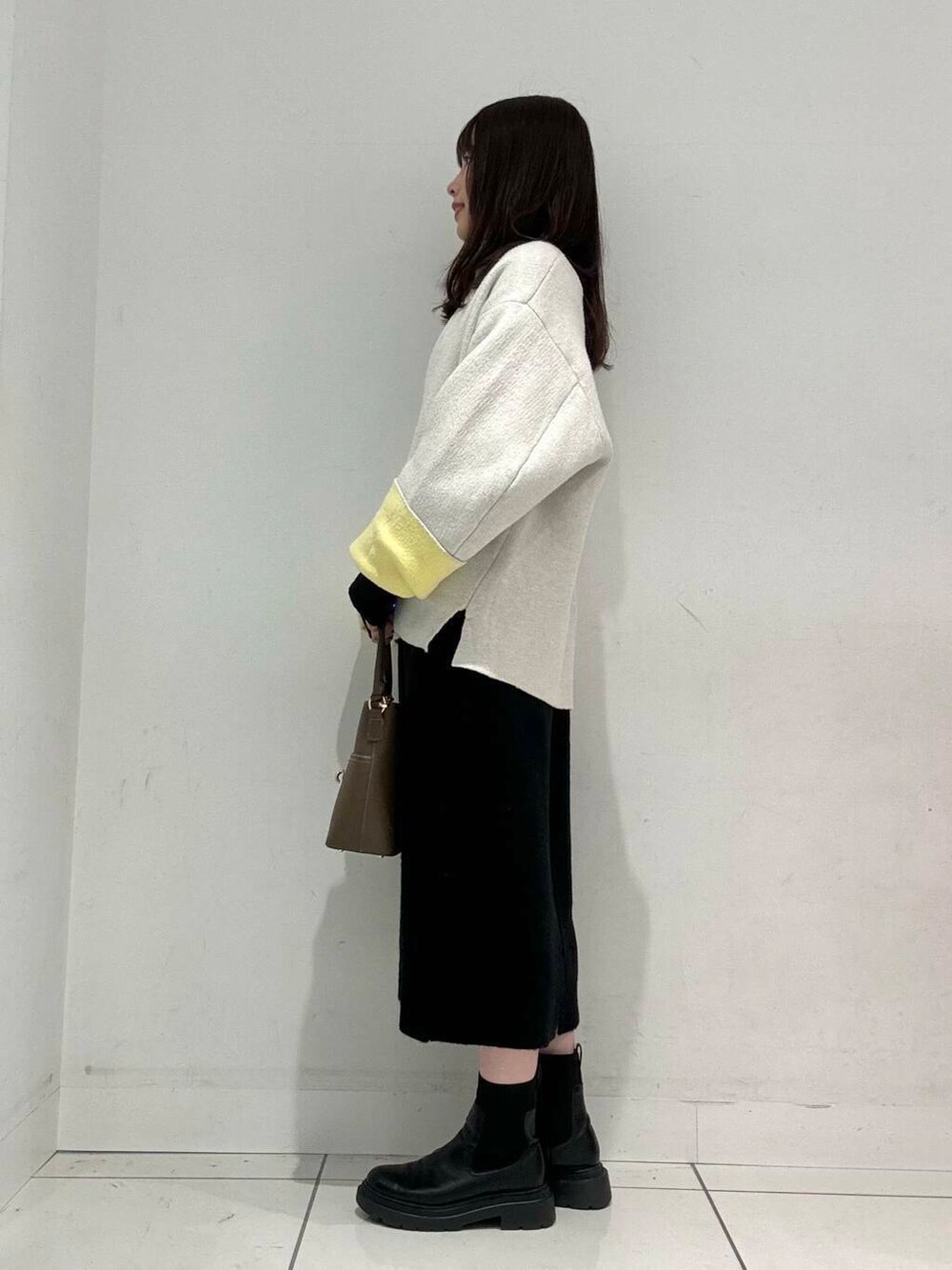 ベージュ系のハンドバッグ、ベージュ系のその他アウター、ブラック系のワンピースを着用したレディースの秋コーディネートの3枚目の写真