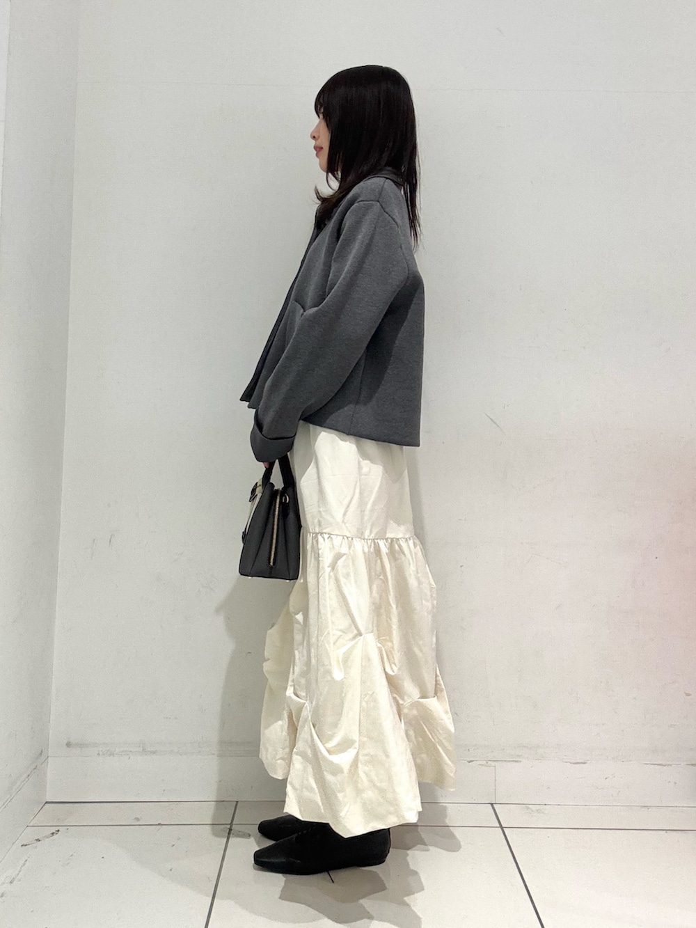 ホワイト系のスカート、ブラック系のその他シューズ、ブラック系のハンドバッグを着用したレディースの冬コーディネートの2枚目の写真
