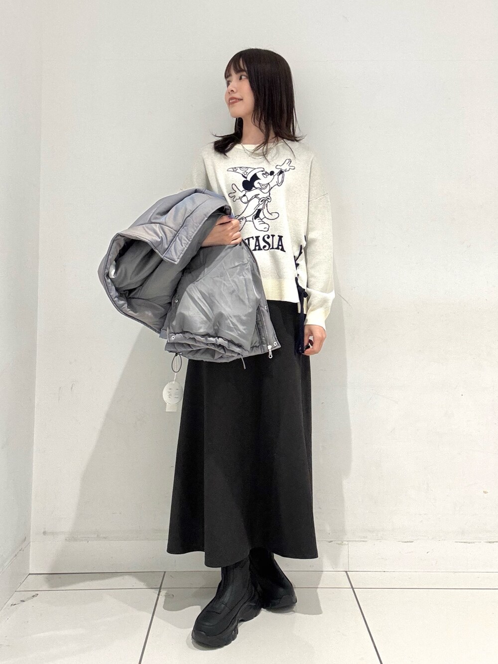 グレー系のスカート、ホワイト系のニット/セーター、グリーン系のダウンジャケット/コートを着用したレディースの秋コーディネートの4枚目の写真