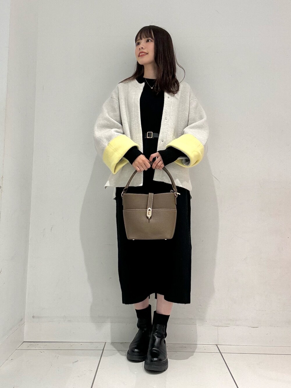 ブラック系のワンピース、ベージュ系のハンドバッグ、ベージュ系のその他アウターを着用したレディースの秋コーディネートの2枚目の写真