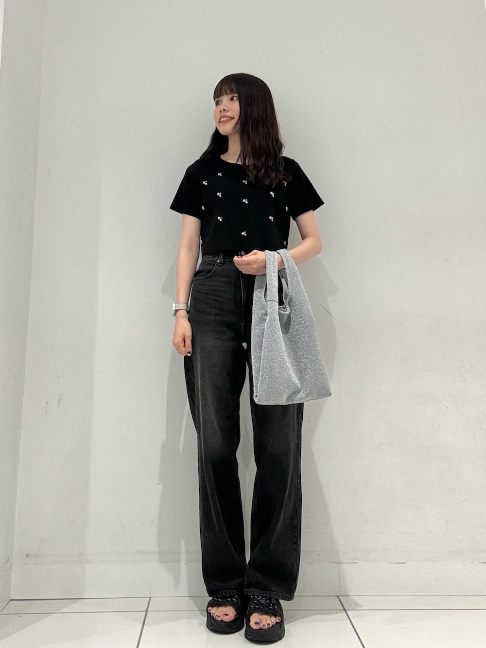 ブラック系のニット/セーター、ブラック系のデニムパンツ、シルバー系のトートバッグを着用したレディースの夏コーディネートの4枚目の写真