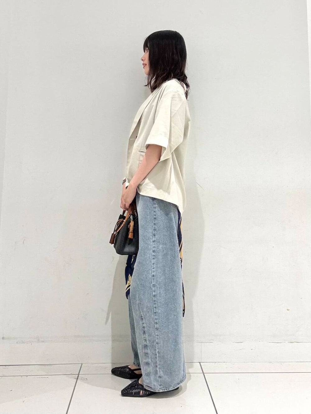 ブラック系のサンダル、ブラック系のトートバッグ、ブルー系のデニムパンツを着用したレディースの夏コーディネートの2枚目の写真