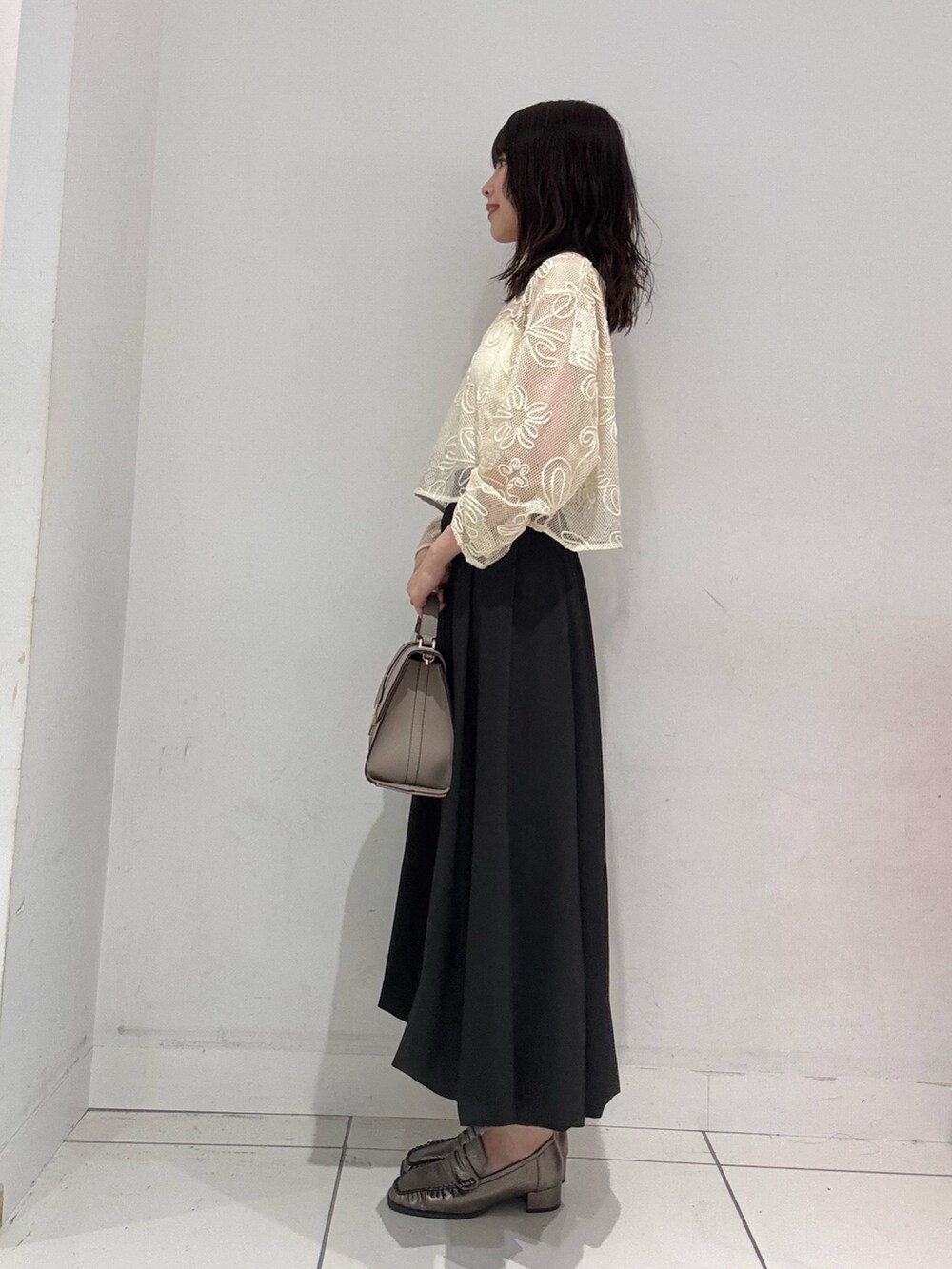 ホワイト系のキャミソール、ホワイト系のTシャツ/カットソー、ブラック系のスカートを着用したレディースの夏コーディネートの2枚目の写真