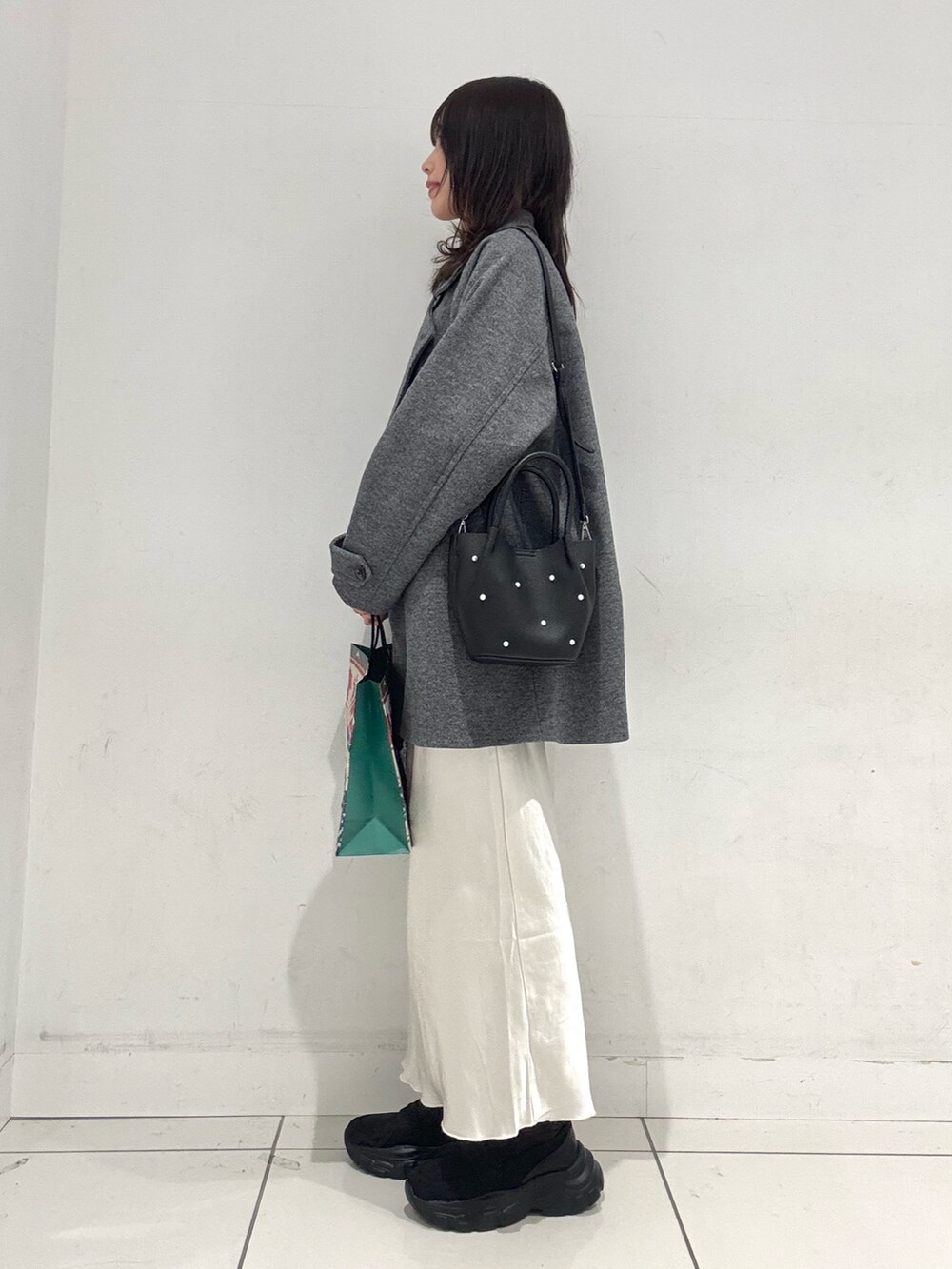 グレー系のその他アウター、イエロー系のニット/セーター、ホワイト系のスカートを着用したレディースの冬コーディネートの2枚目の写真