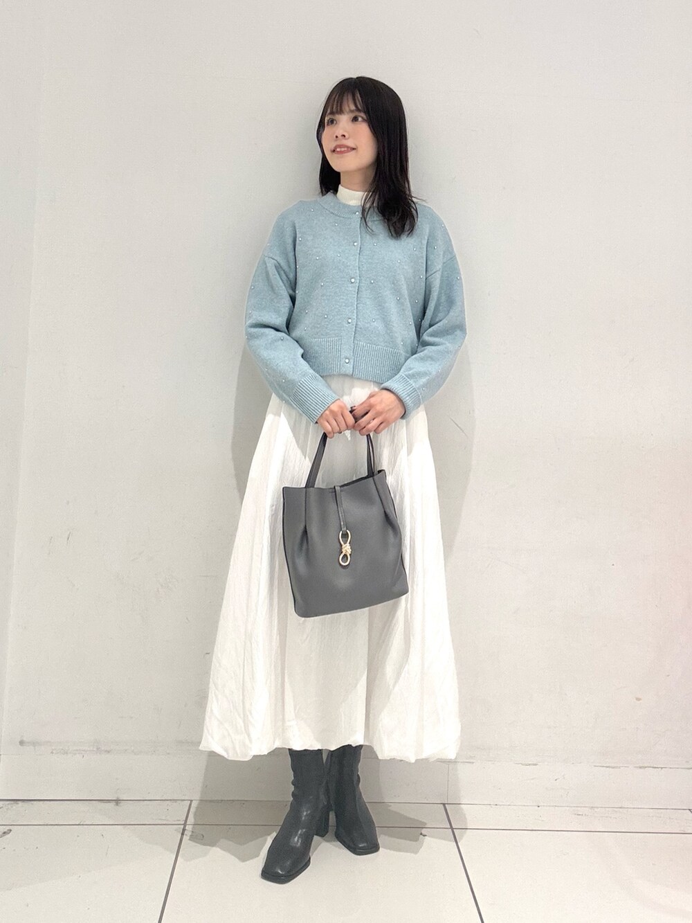 ホワイト系のスカート、グレー系のトートバッグ、ブラック系のブーツを着用したレディースの秋コーディネートの4枚目の写真