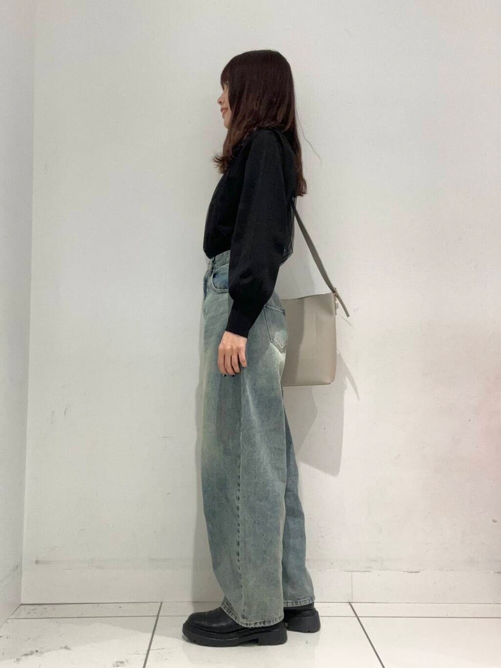 ブルー系のデニムパンツ、ベージュ系のショルダーバッグ、ブラック系のニット/セーターを着用したレディースの秋コーディネートの2枚目の写真