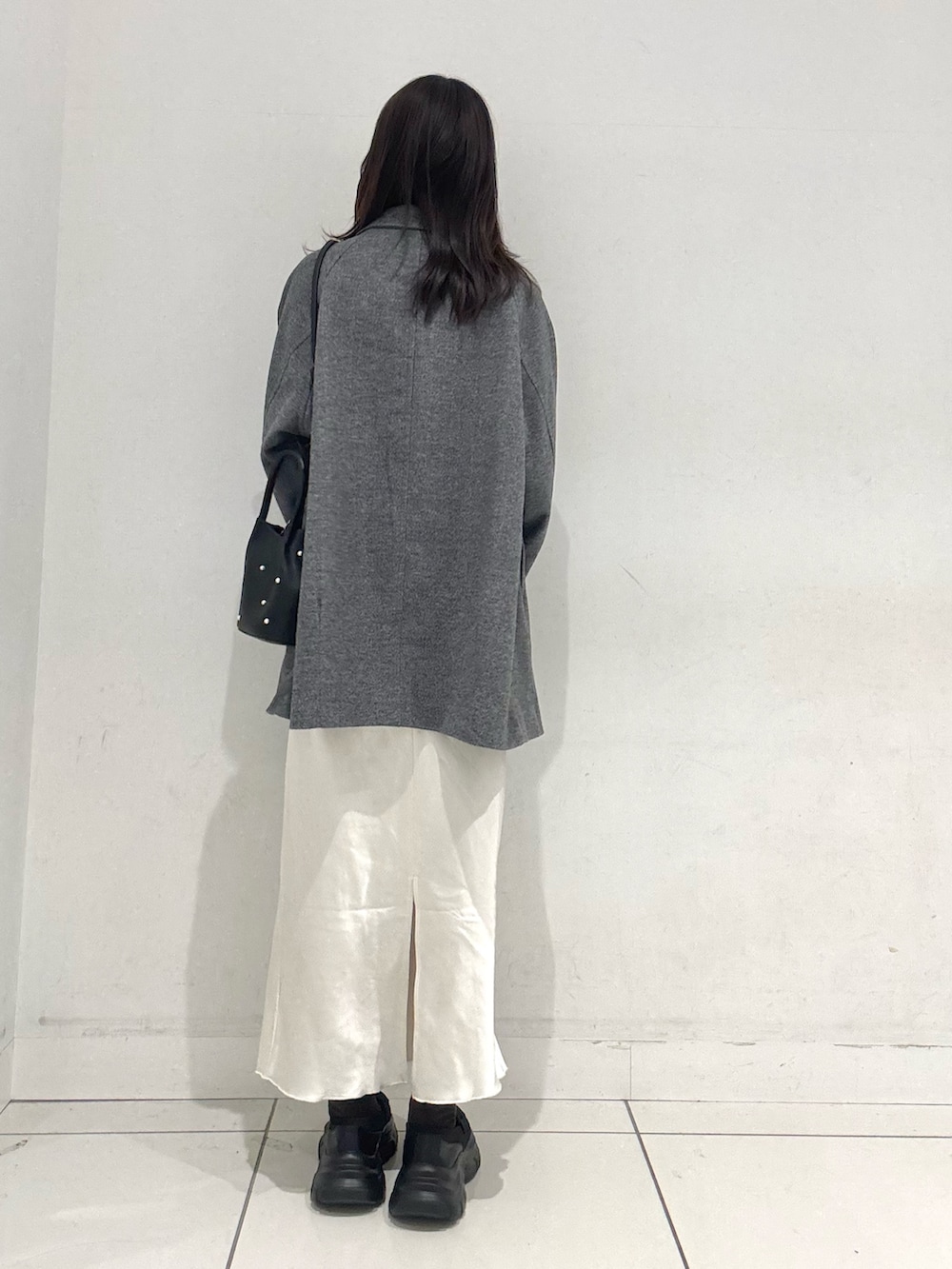 グレー系のその他アウター、イエロー系のニット/セーター、ホワイト系のスカートを着用したレディースの冬コーディネートの3枚目の写真