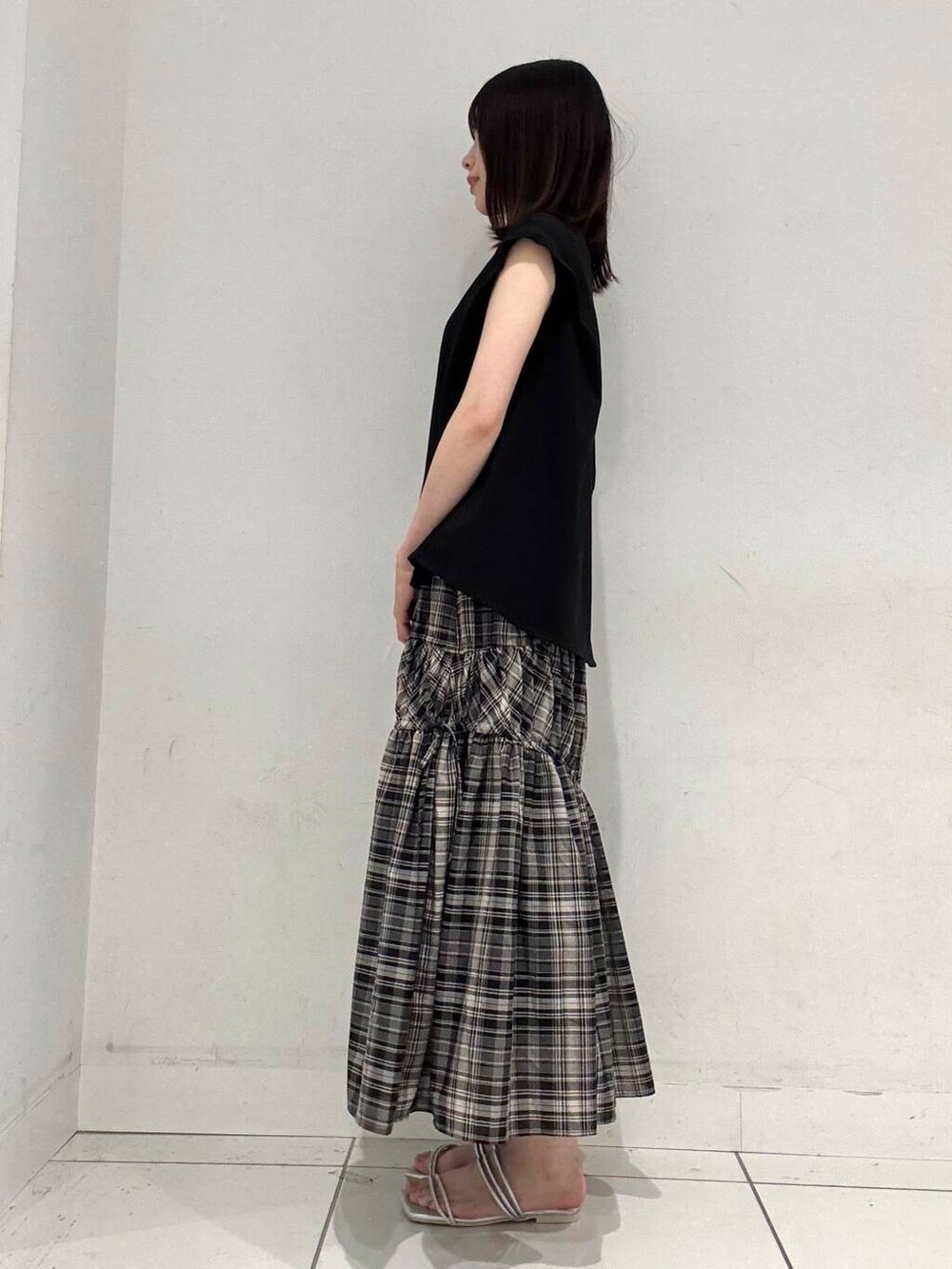 シルバー系のハンドバッグ、シルバー系のサンダル、ブラック系のTシャツ/カットソーを着用したレディースの夏コーディネートの2枚目の写真