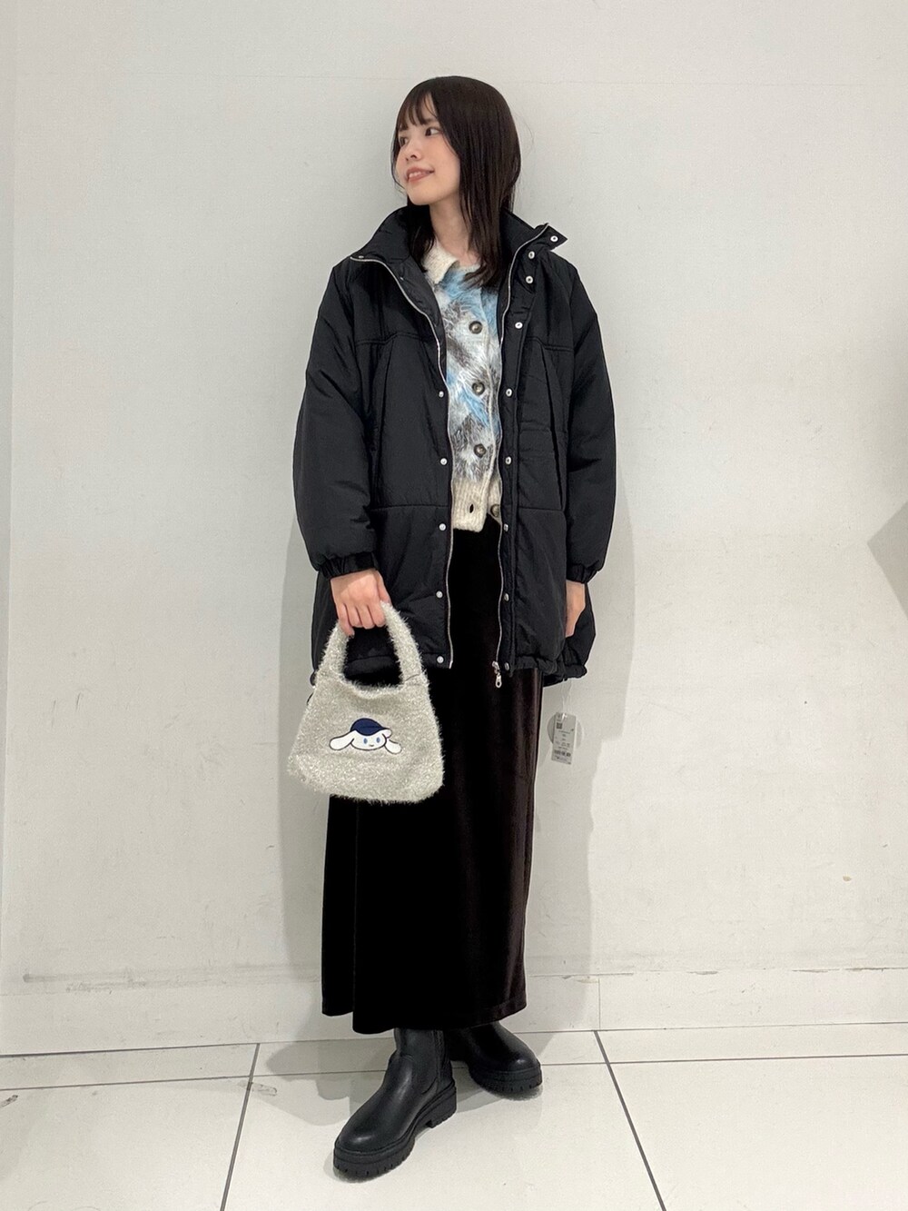 ブルー系のカーディガン/ボレロ、ブラック系のダウンジャケット/コート、ブラウン系のスカートを着用したレディースの冬コーディネートの4枚目の写真